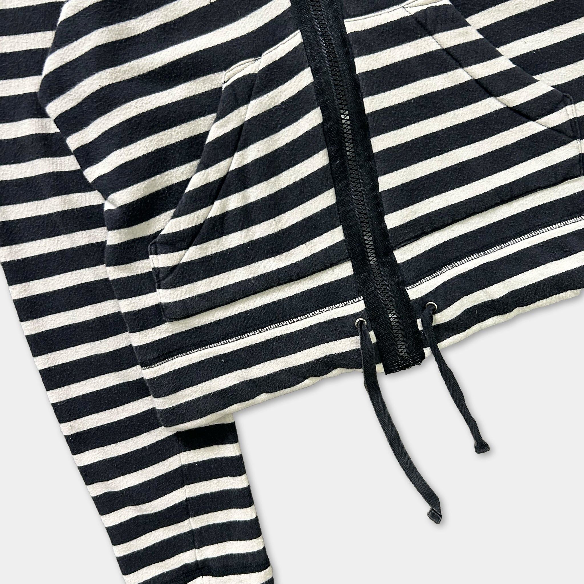 A close-up view of a black and white striped hoodie with a zipper and drawstring.