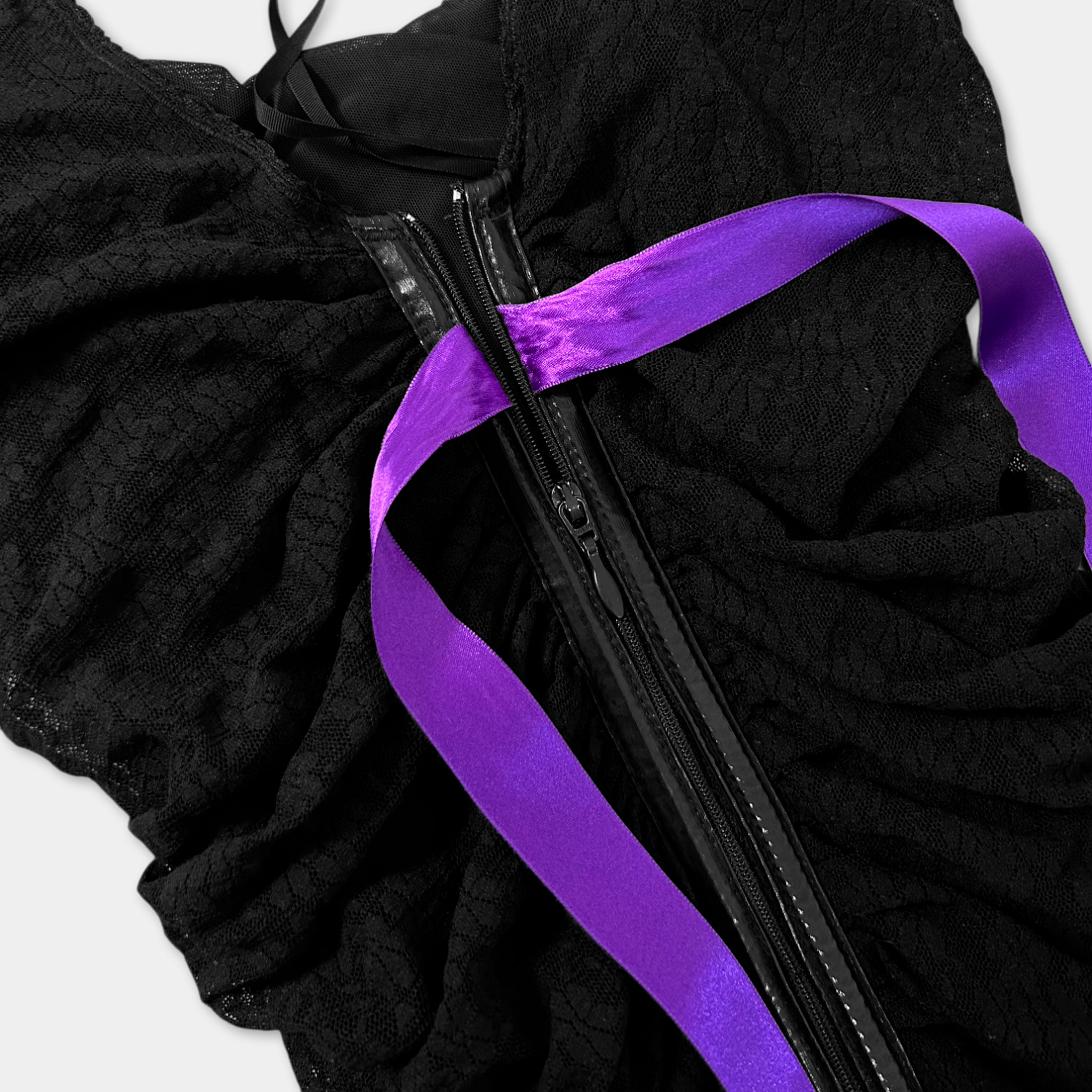 A close-up view of a black lace dress with a purple ribbon tied around the waist.
