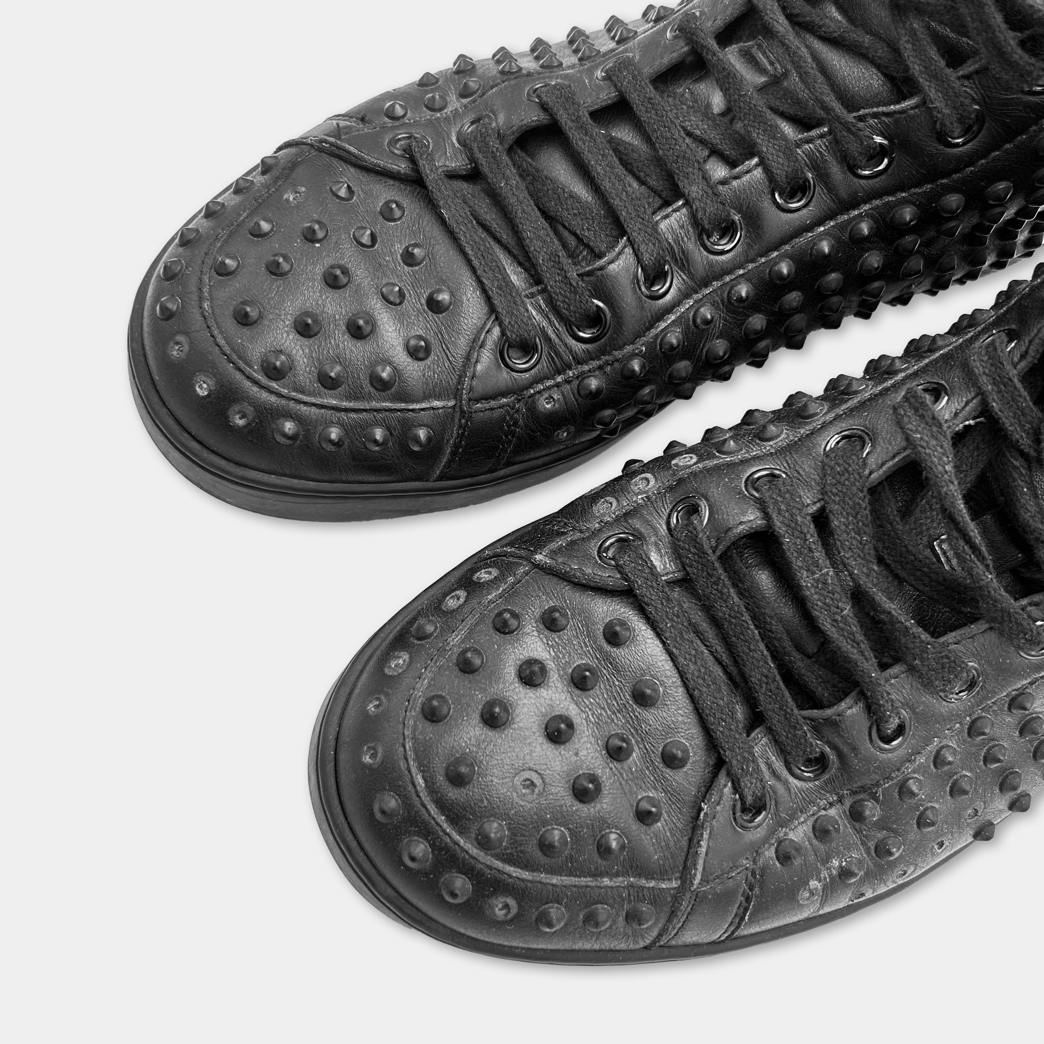 A pair of black leather sneakers with a distinctive studded design.