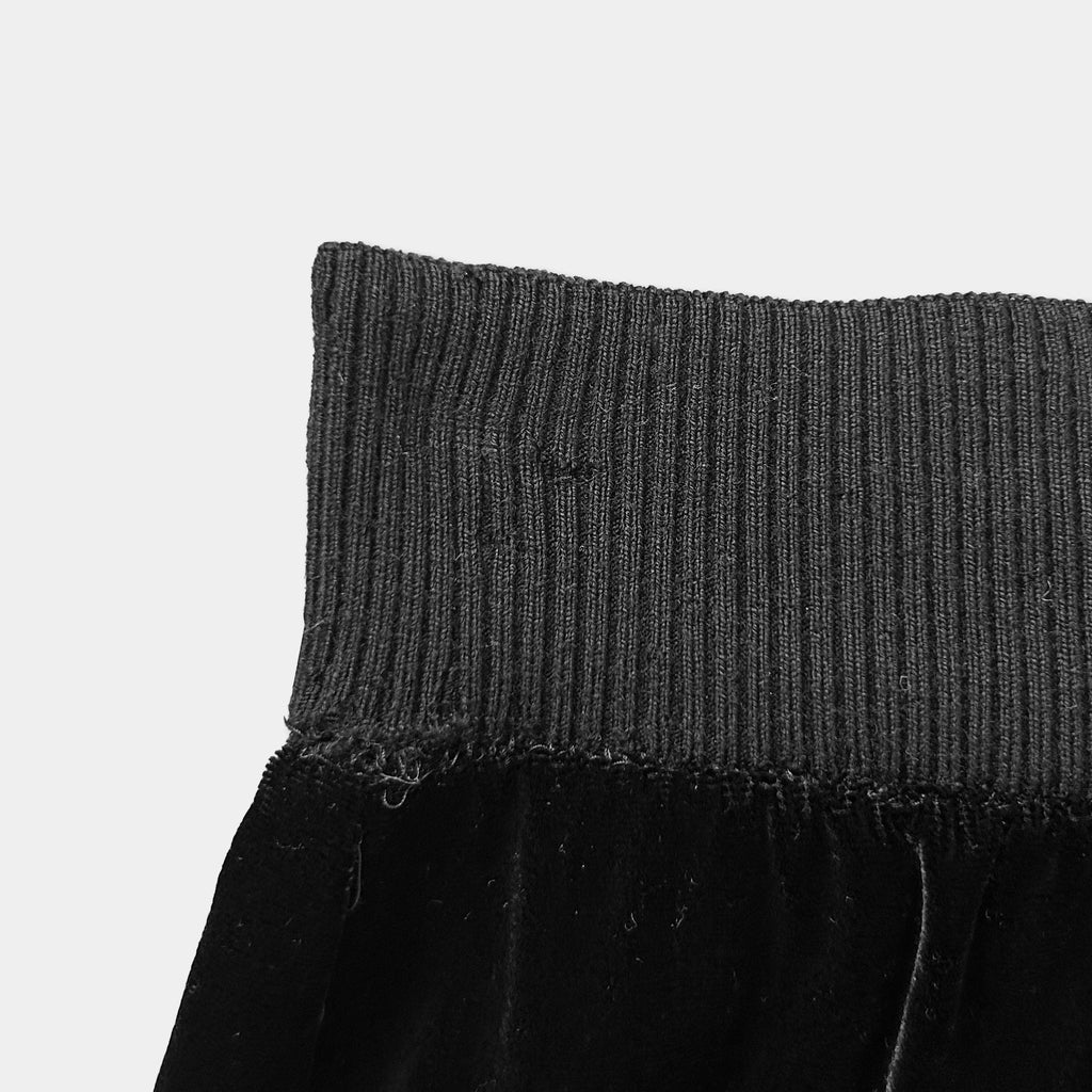 A close-up view of a black, knitted or ribbed waistband of a garment.