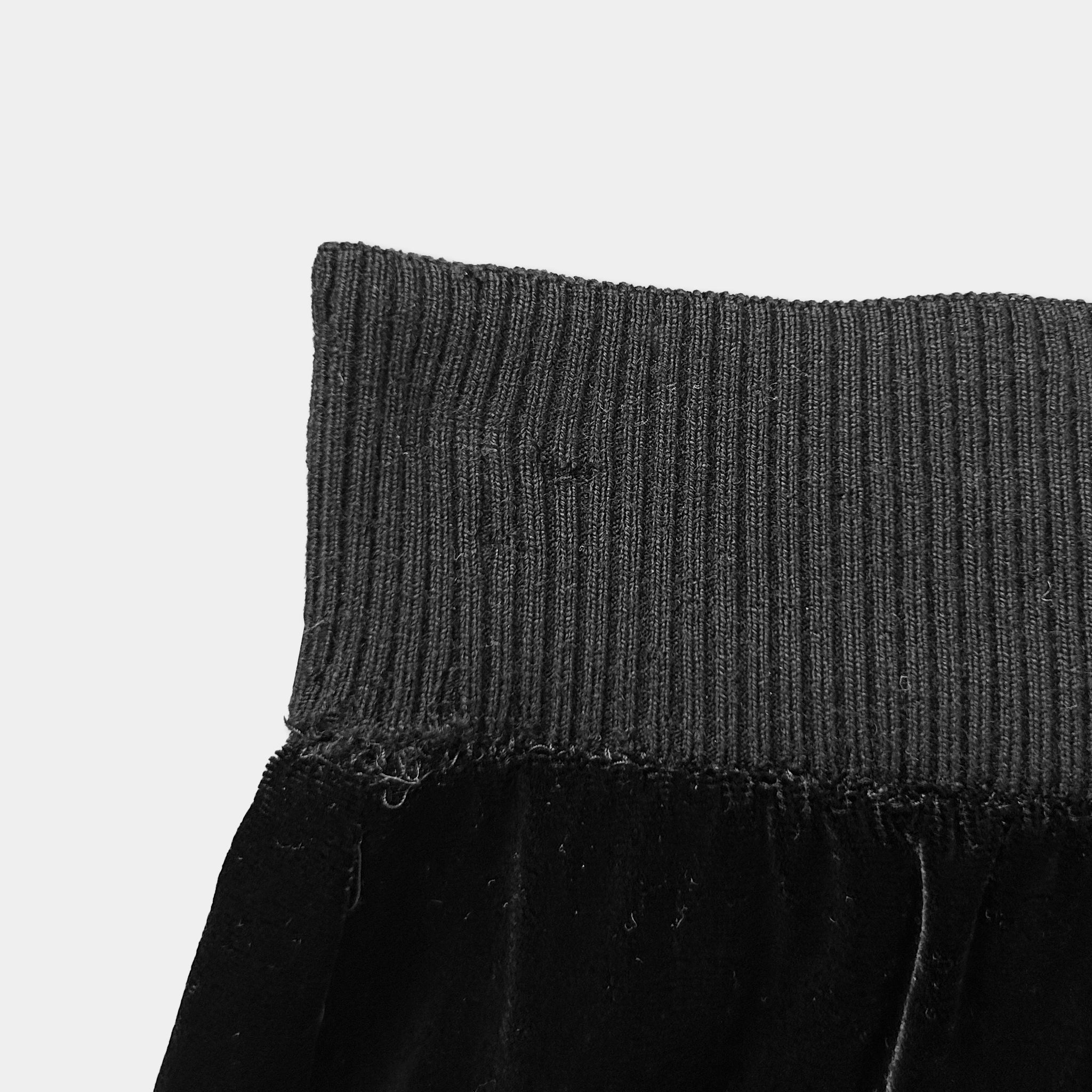 A close-up view of a black, knitted or ribbed waistband of a garment.