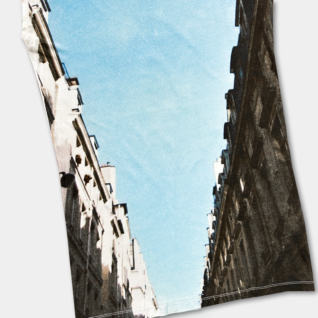 a narrow street with tall buildings on either side, creating a sense of depth and perspective.