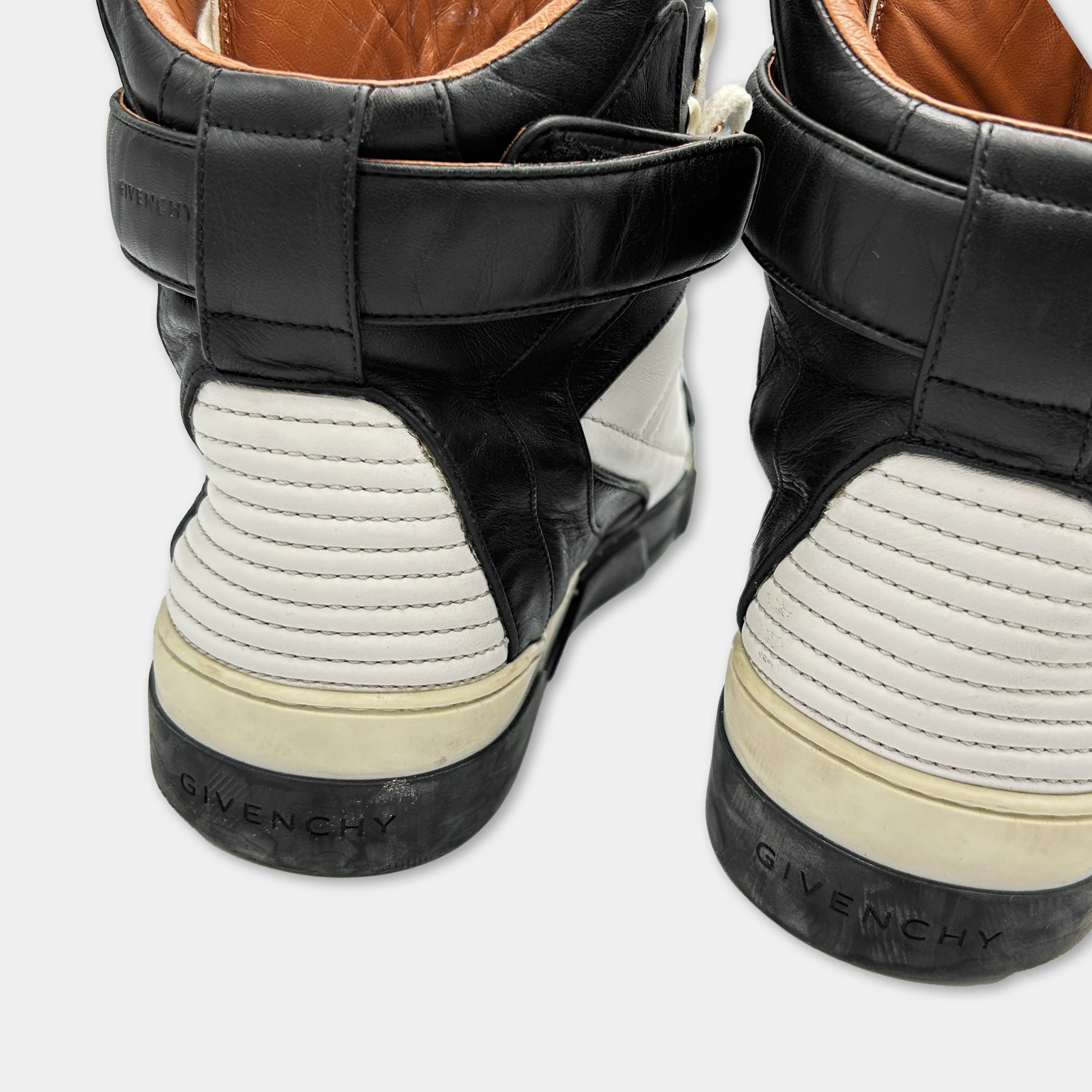A close-up view of a pair of black and white high-top sneakers with the Givenchy brand logo visible on the back.