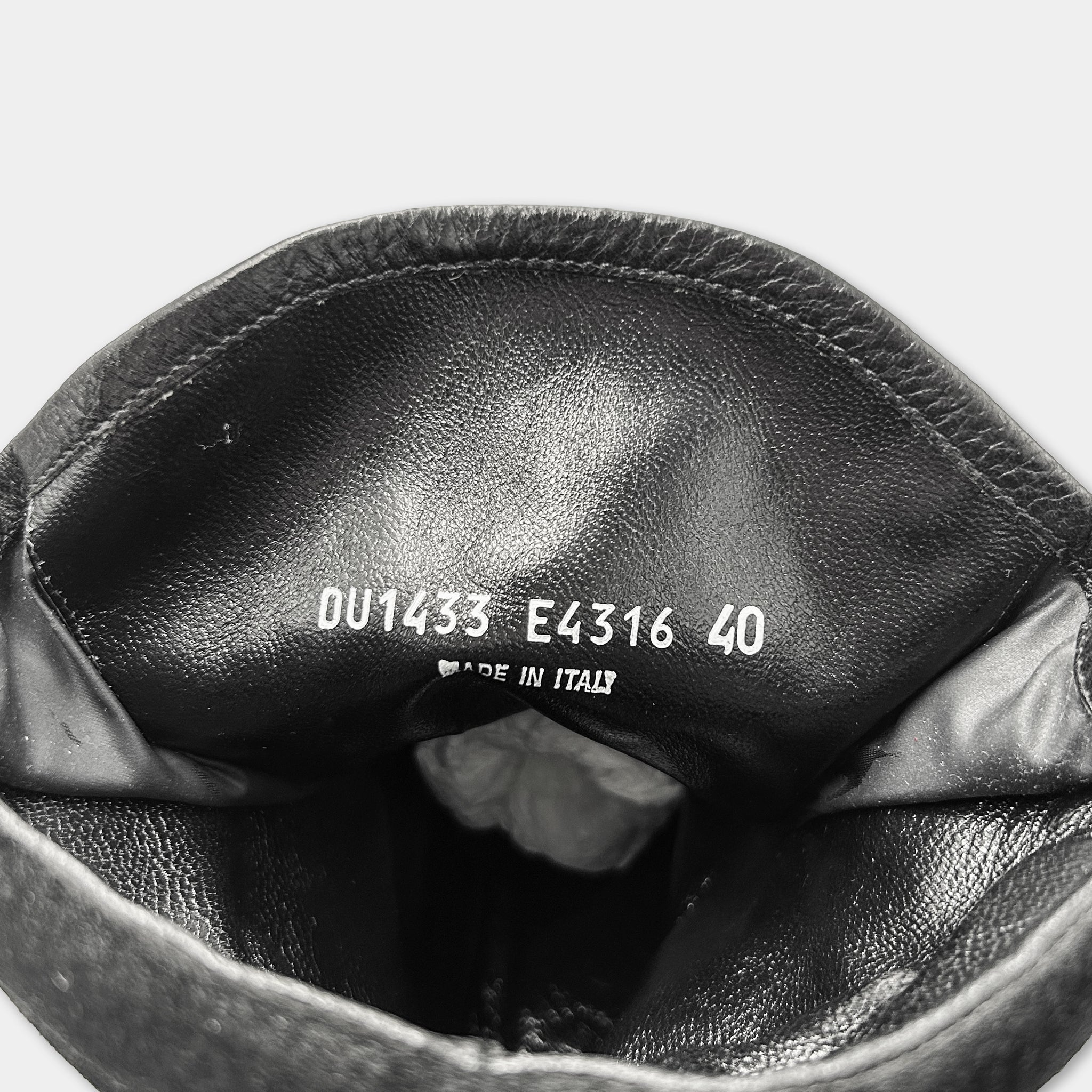 the inside of a black leather boot, with the brand name and model number printed on the leather.