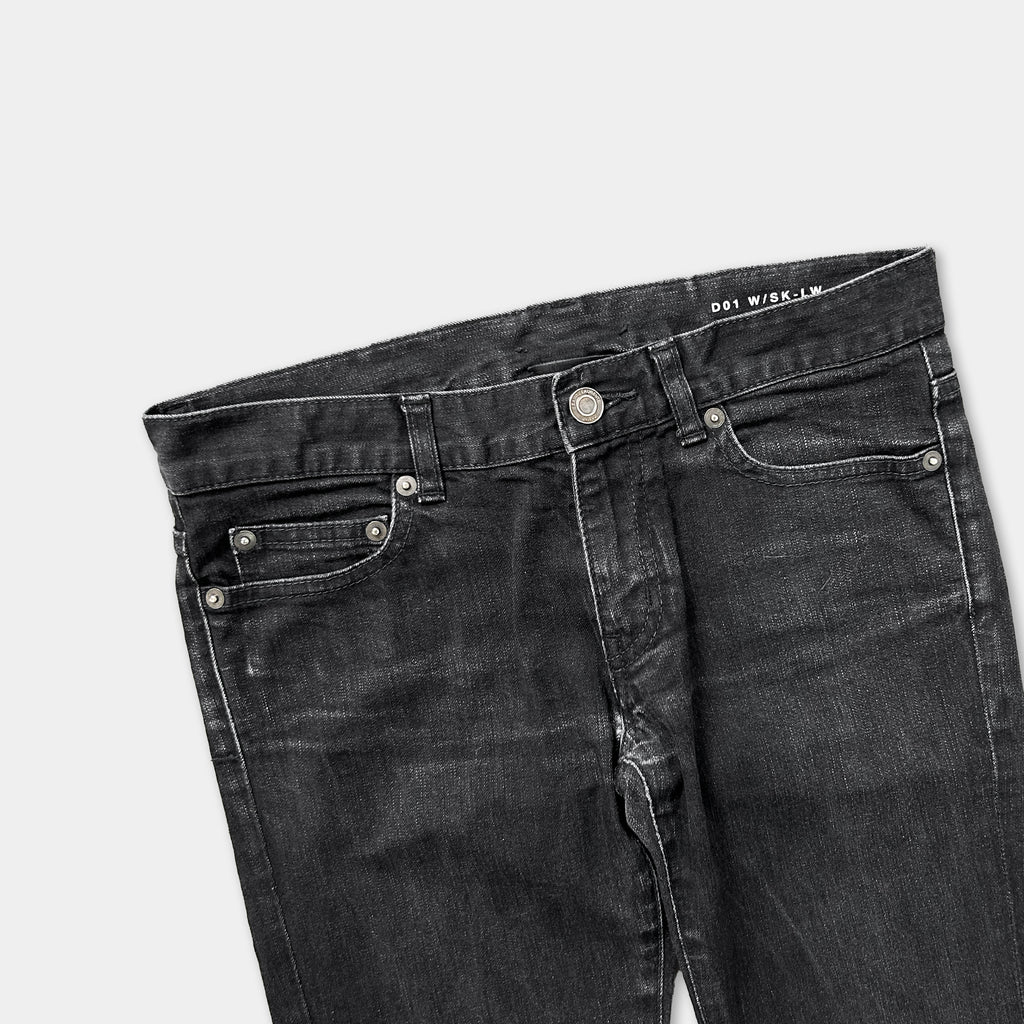A pair of black jeans with a zipper and buttons, laid out against a white background.
