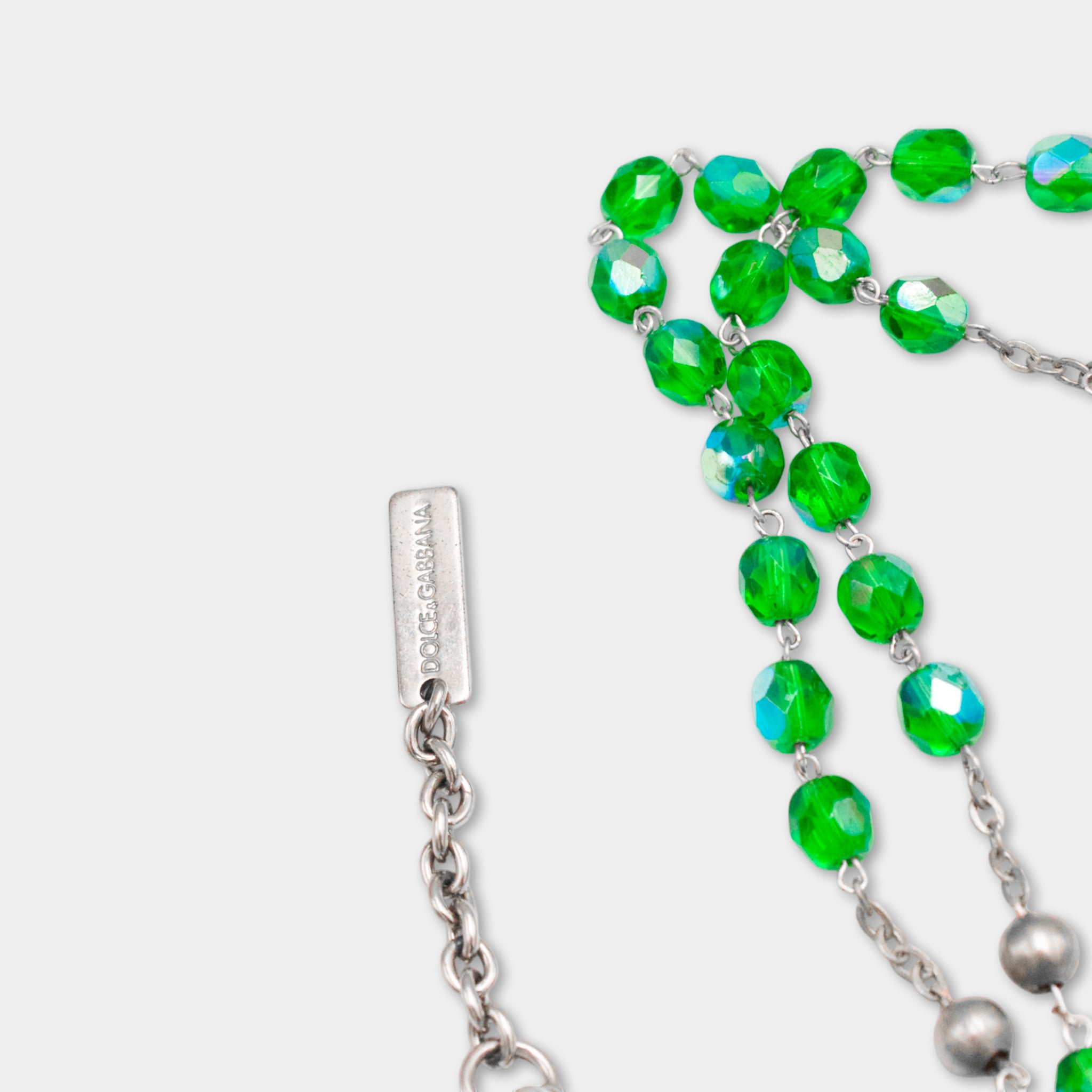 A close-up view of a necklace with green crystal beads and a metal clasp.