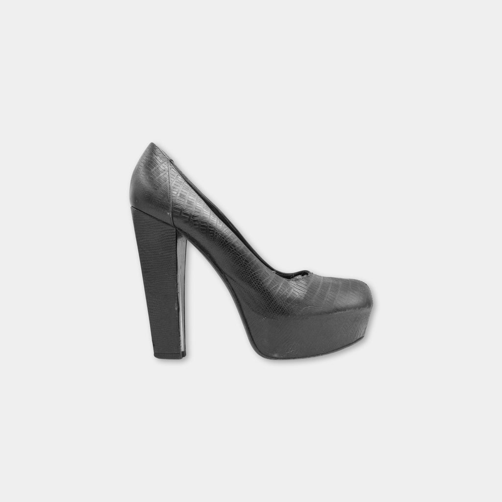 A single black high-heeled shoe with a pointed toe and a platform sole.