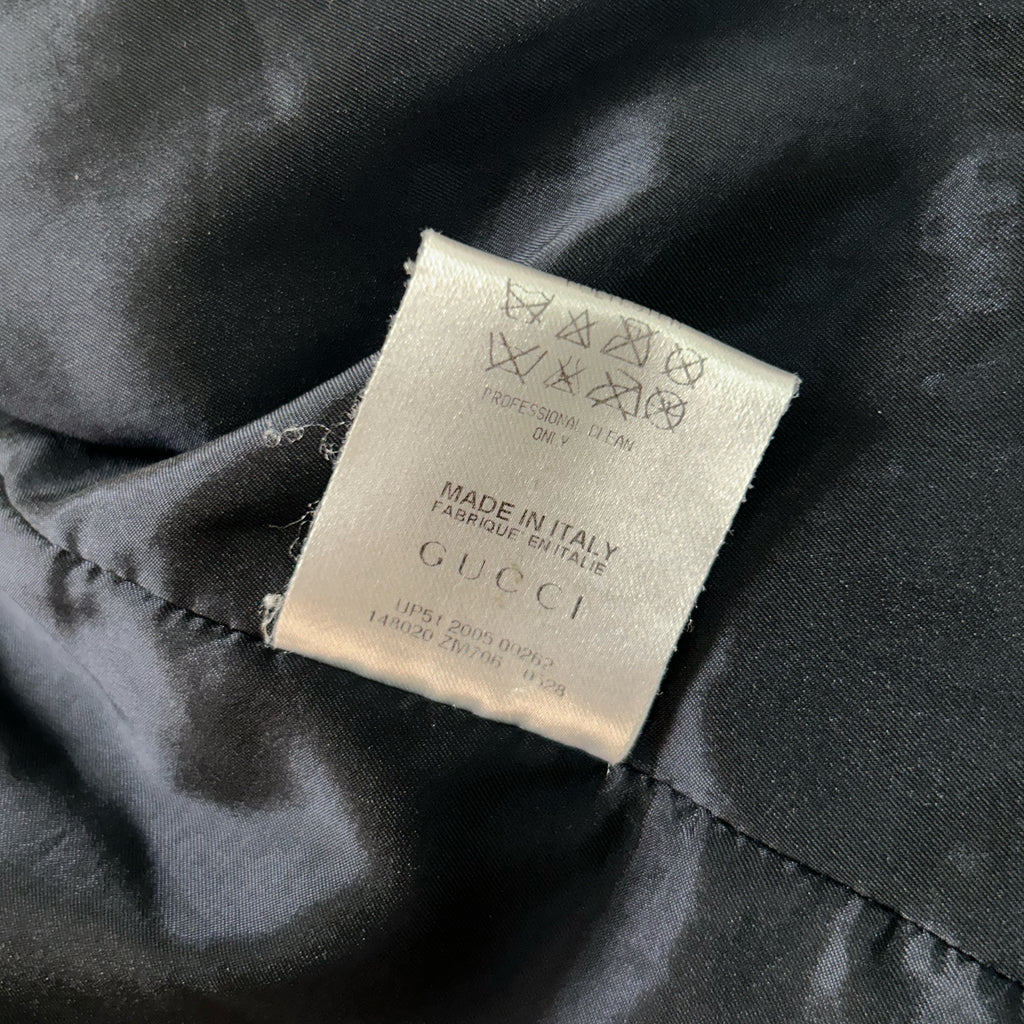 a close-up view of a Gucci label on a black fabric, indicating that the garment is made in Italy and is a high-quality product.