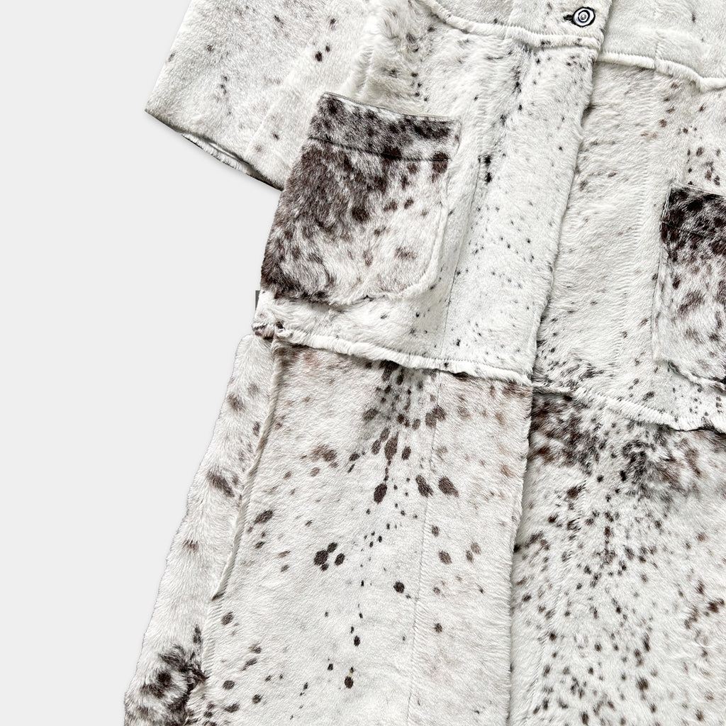 a close-up view of a white fur coat with a pattern of brown spots.