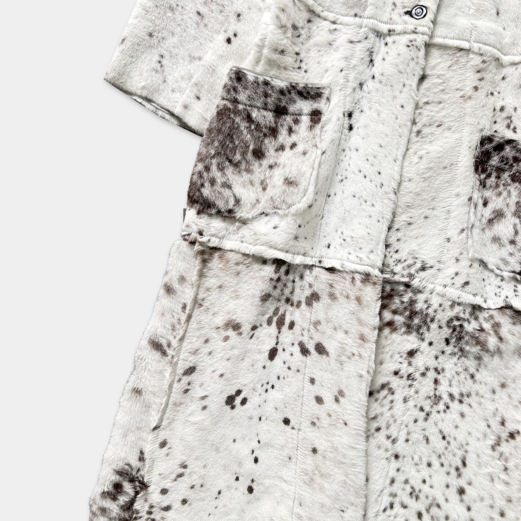 a close-up view of a white fur coat with a pattern of brown spots.