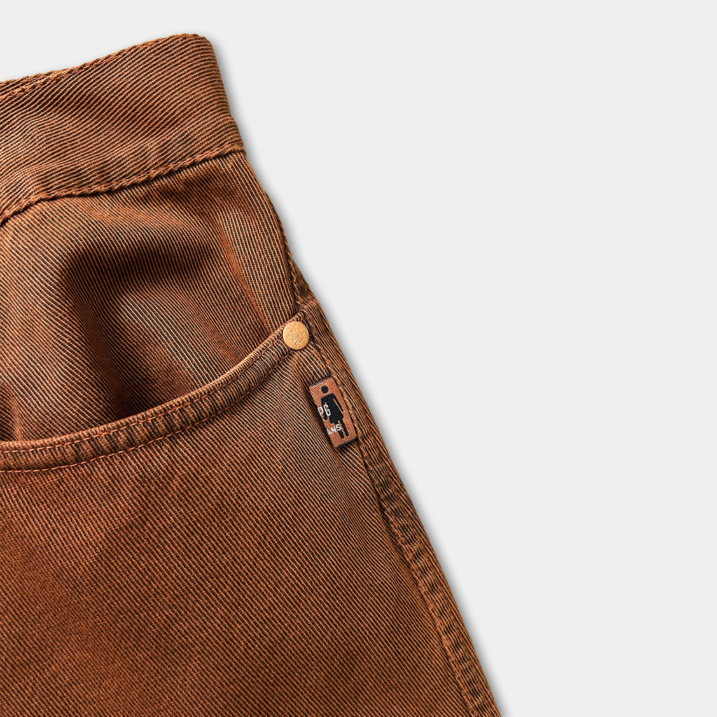 A pair of brown jeans with a pocket and a small tag attached to the pocket.