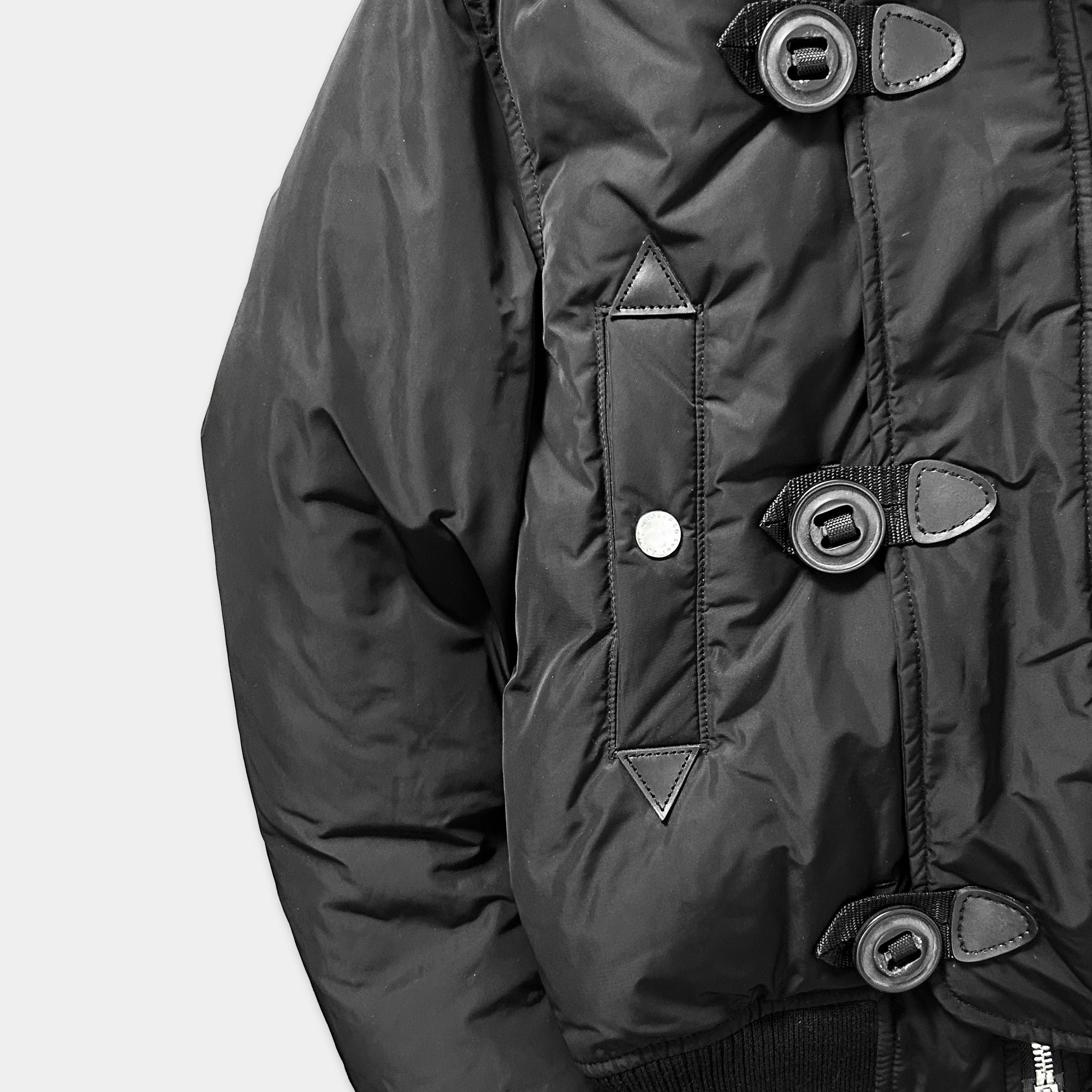 A close-up view of a black jacket with three buttons and a zipper.