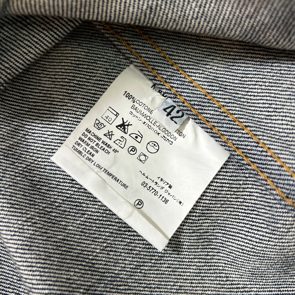 a close-up view of a denim fabric, specifically a pair of jeans, with a label attached to it. The label provides information about the fabric, such as the material and the brand.