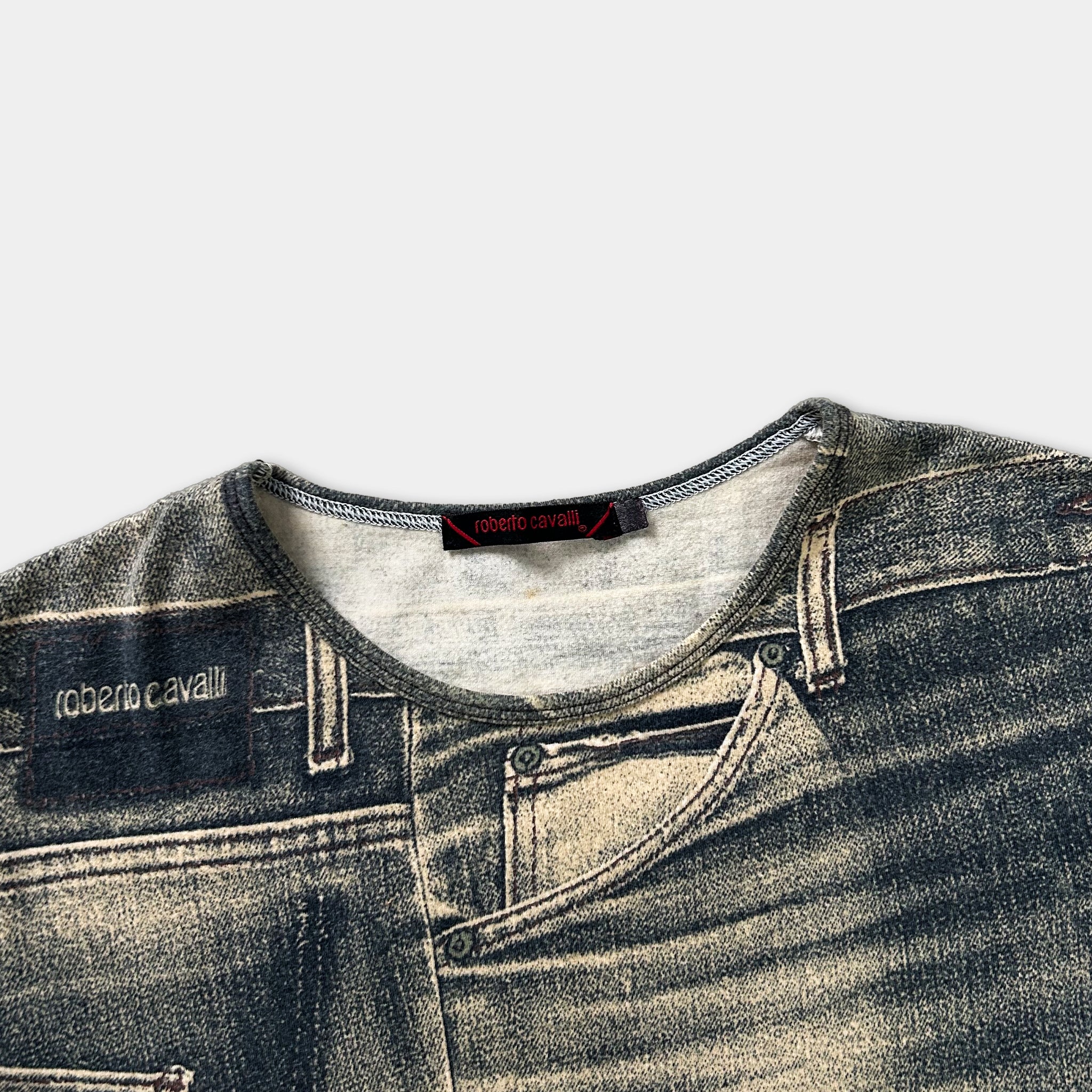 A close-up view of a pair of gray and black jeans, with a label on the left side that reads "roberta cavalli".