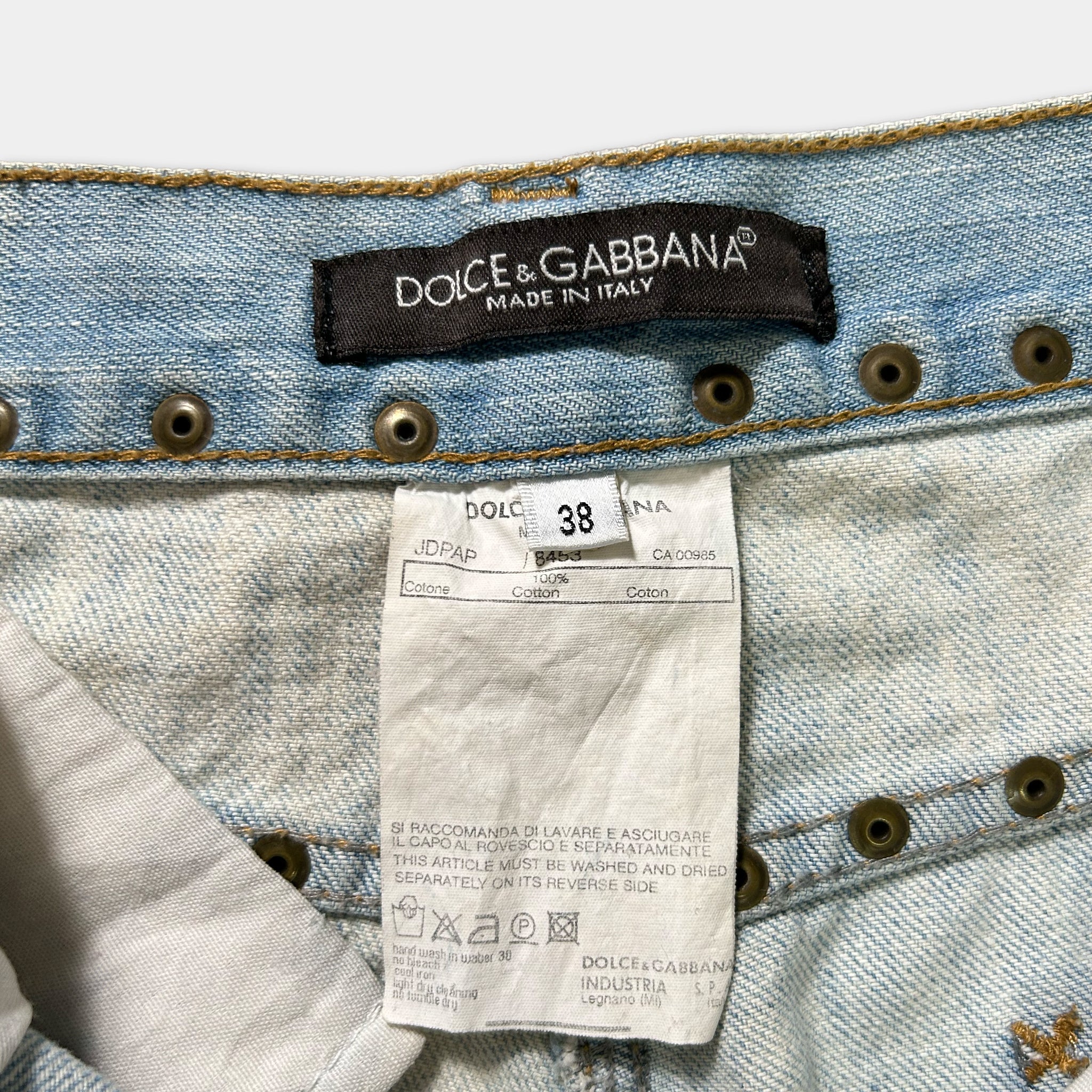 a close-up view of a pair of blue denim jeans with a label attached to the waistband, indicating the brand and the country of manufacture.