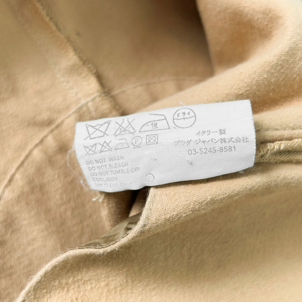 a close-up view of a beige fabric, possibly a piece of clothing, with a label attached to it. The label contains instructions and symbols, likely related to the care and washing of the fabric.