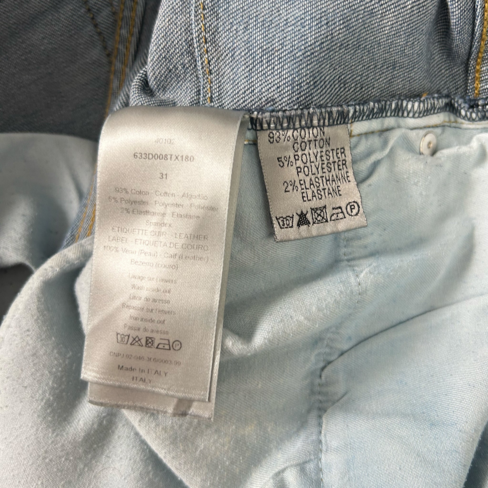 a close-up view of a denim fabric, with a label attached to it. The label provides information about the fabric, such as the material and the type of polyester used.
