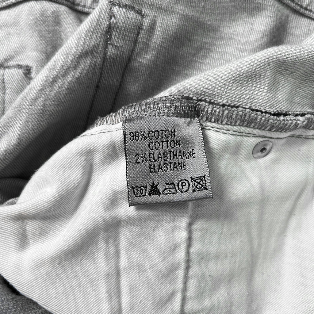 A close-up of a fabric label on a pair of jeans, indicating the material and care instructions.