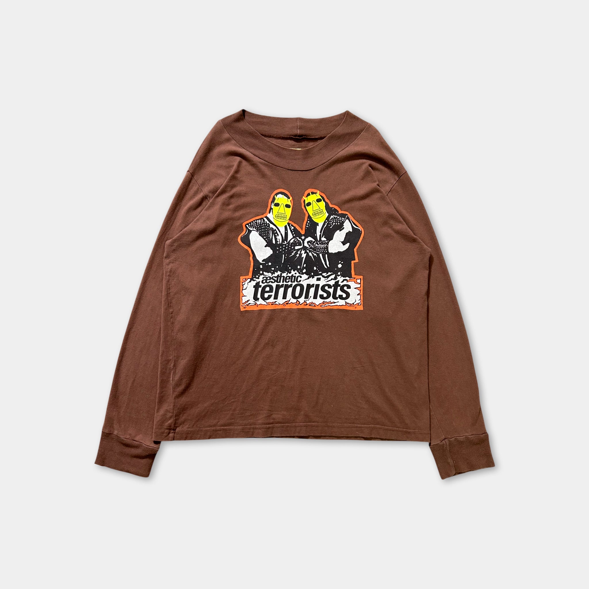 The image is a brown long-sleeved shirt with a graphic design on the front. The design features two people wearing masks, and the word "TERRIFIC" is written below them.