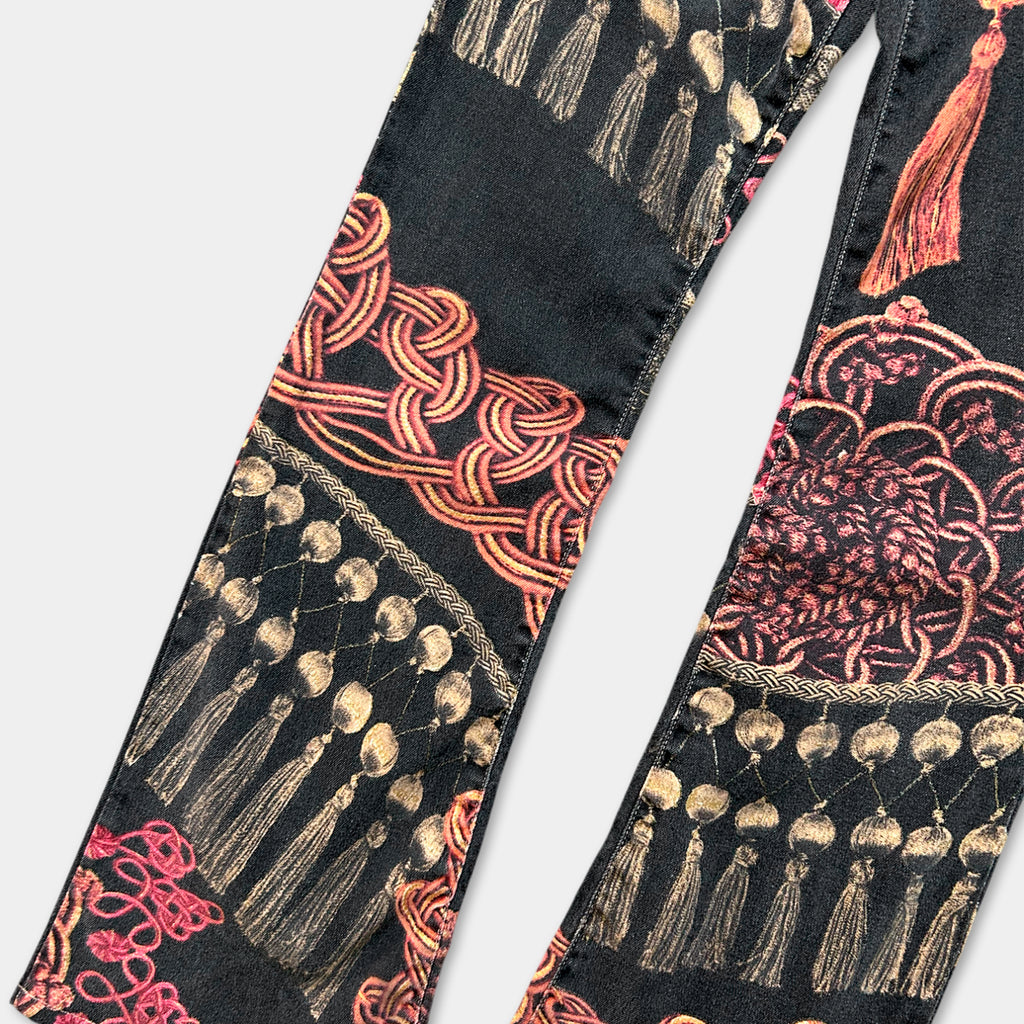 a pair of black jeans with a vibrant, colorful pattern featuring tassels and beads on the fabric.