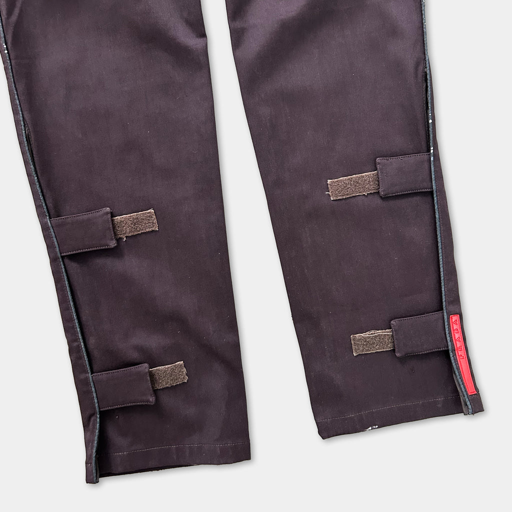 A pair of dark-colored pants with a red label on the right leg.