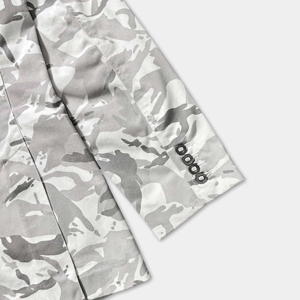 a close-up view of a grey camouflage jacket with a black button on the sleeve.