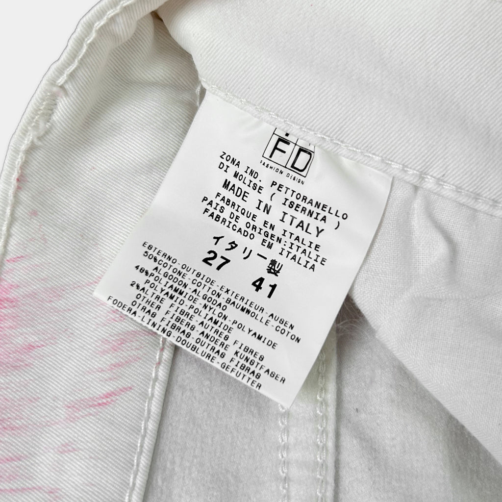 a close-up view of a white label on a piece of clothing, likely a pair of jeans, with text detailing the brand and product information.