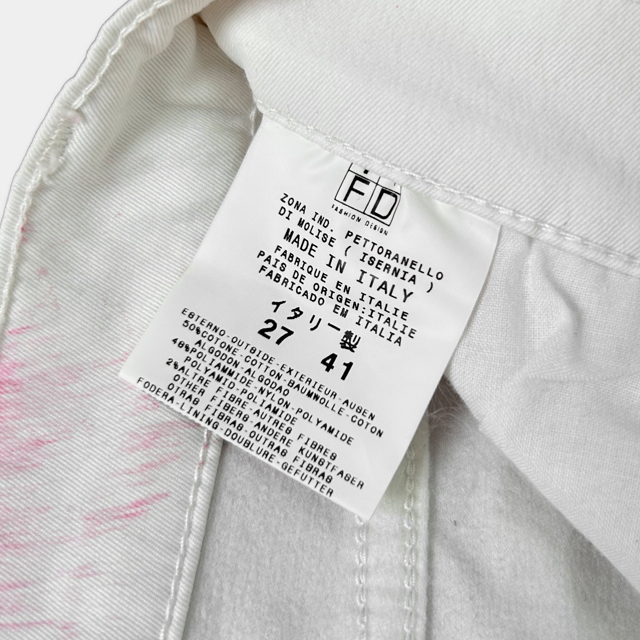 a close-up view of a white label on a piece of clothing, likely a pair of jeans, with text detailing the brand and product information.