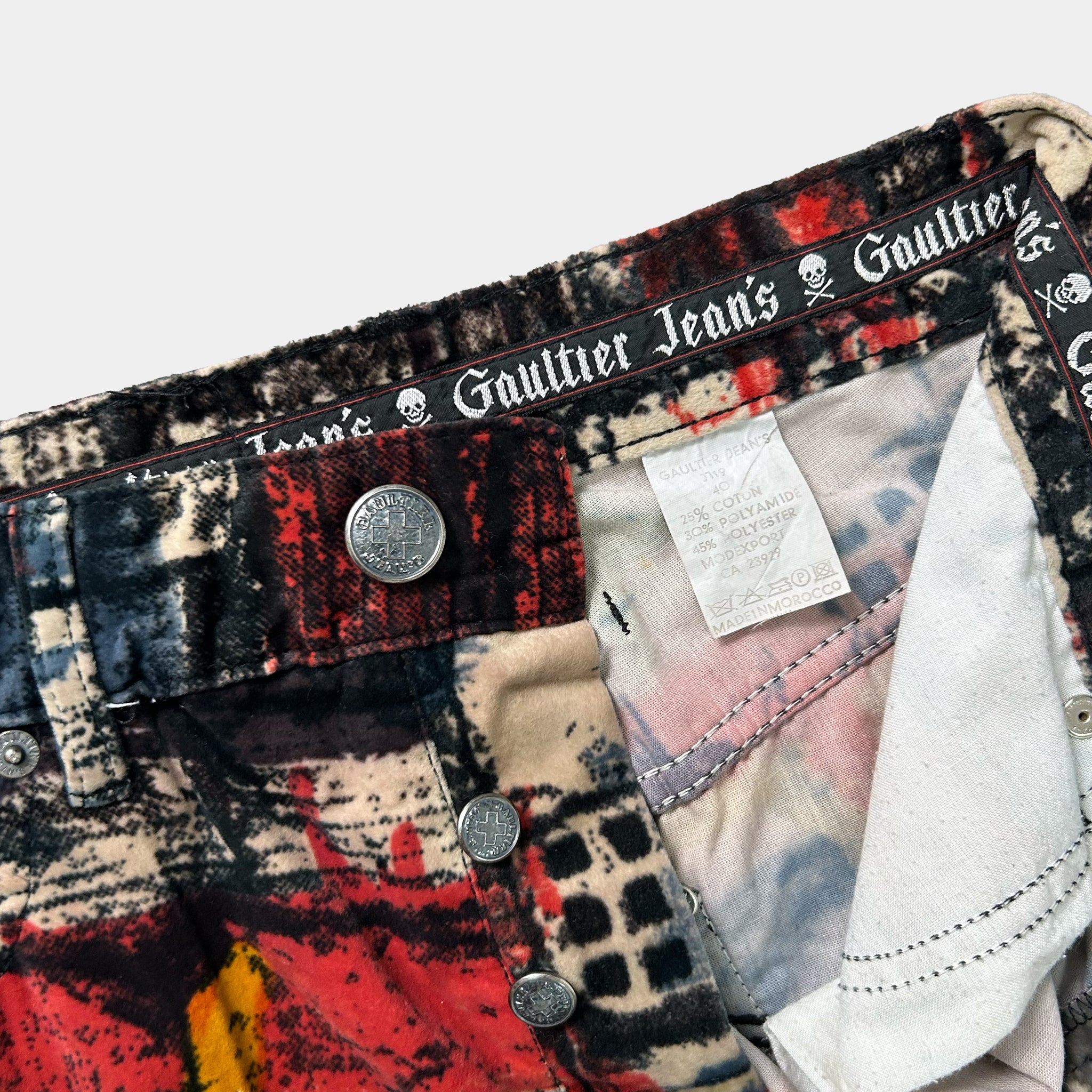 a close-up view of a pair of colorful, patterned jeans with a label attached to the waistband.