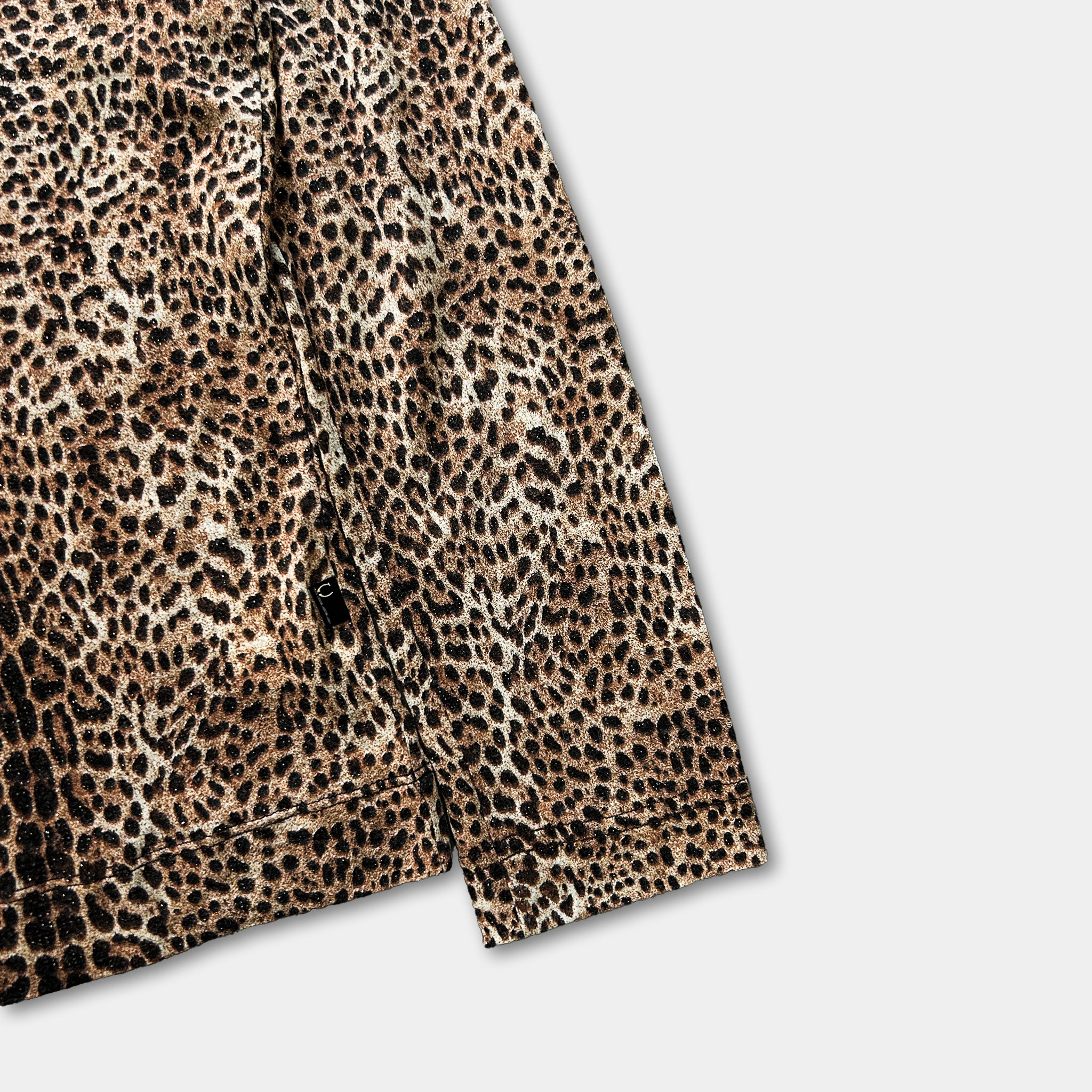 A close-up view of a leopard print jacket or shirt, showcasing the distinctive pattern of brown and black spots.