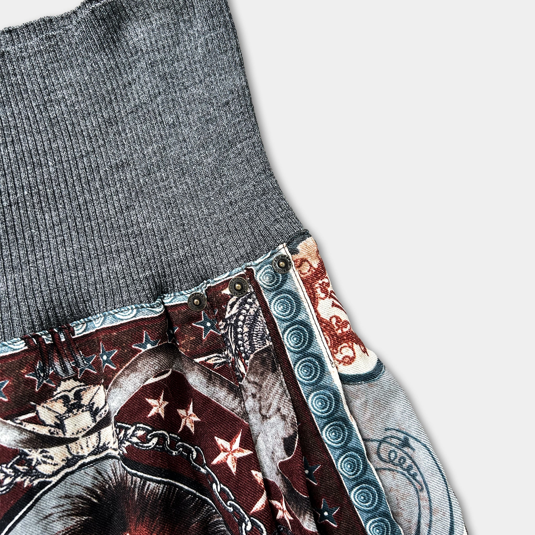 a close-up view of a gray sweater with a patterned design, including stars, a skull, and other decorative elements.