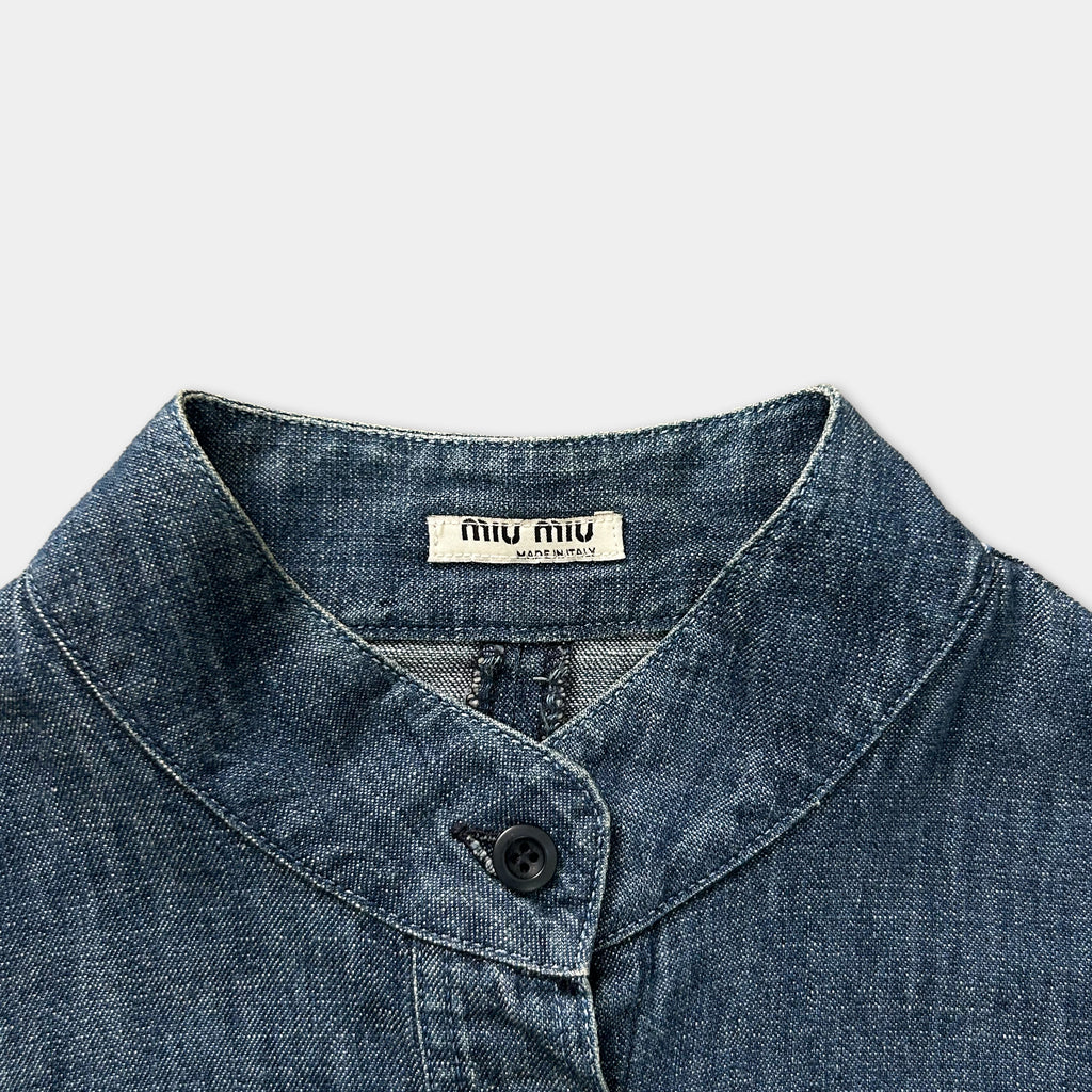 A close-up view of a blue denim shirt collar with a label on it.