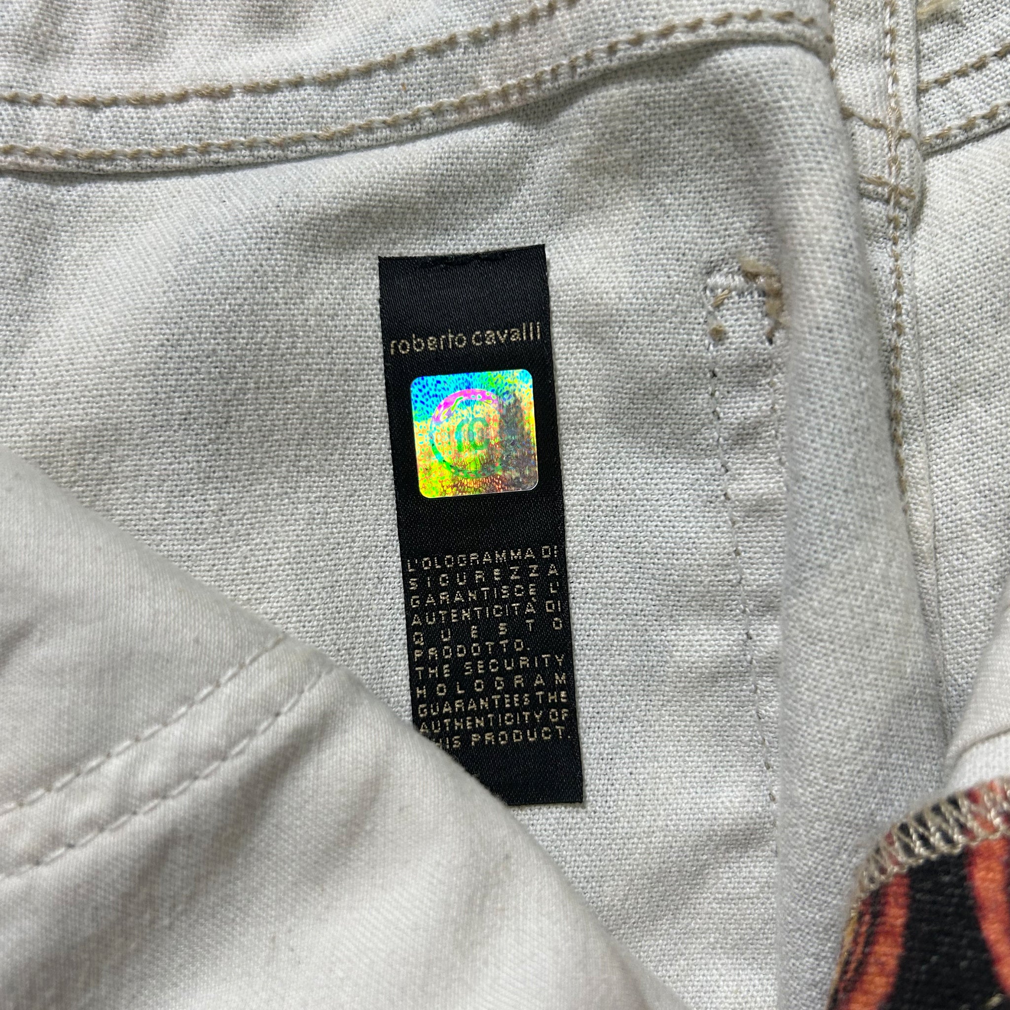 a close-up view of a white fabric, possibly a piece of clothing, with a black label attached to it. The label appears to contain text and possibly a logo or branding, but the image does not contain any text that can be described in fewer than 500 characters.