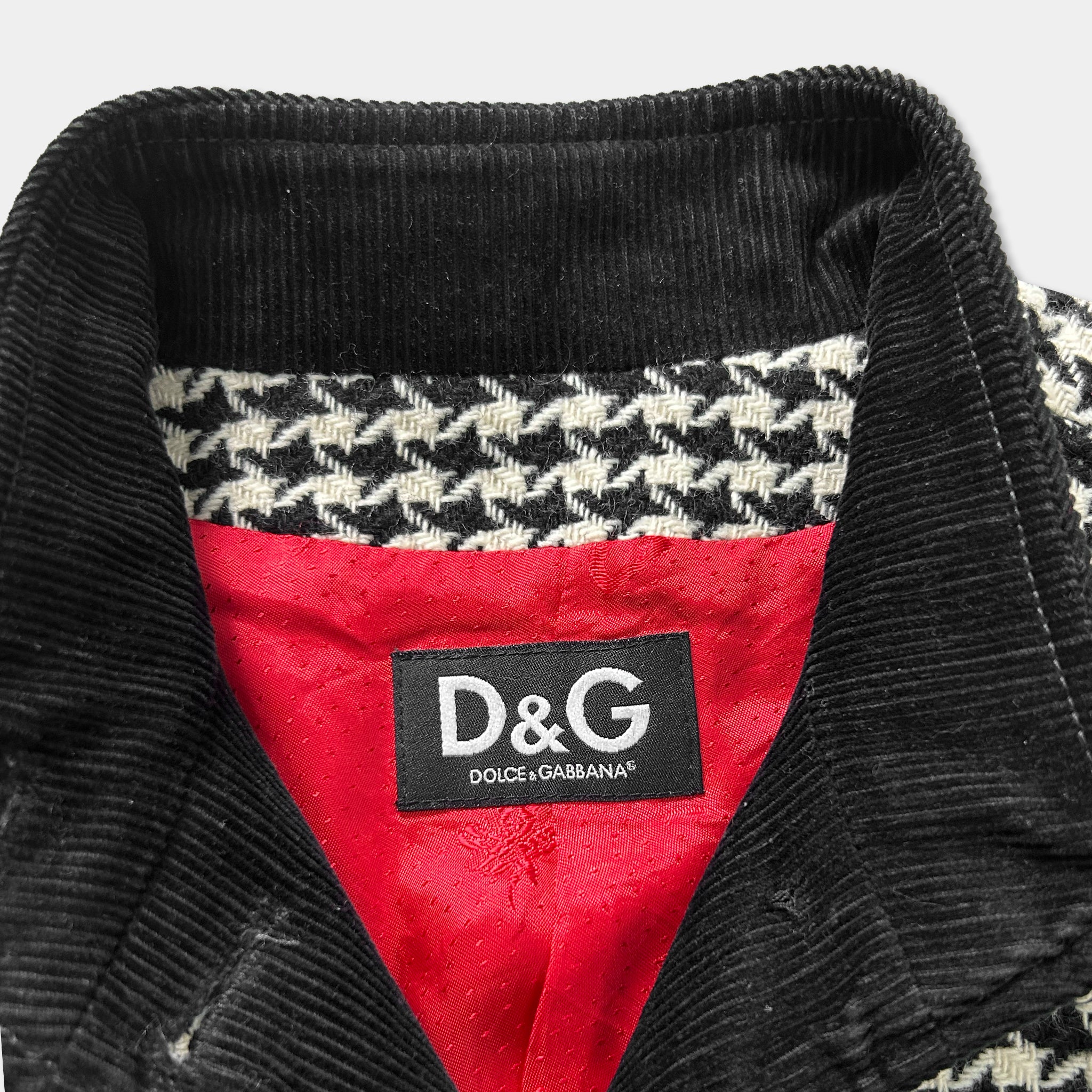 a close-up view of a collar and a red lining inside a jacket, with a black and white houndstooth pattern on the jacket.