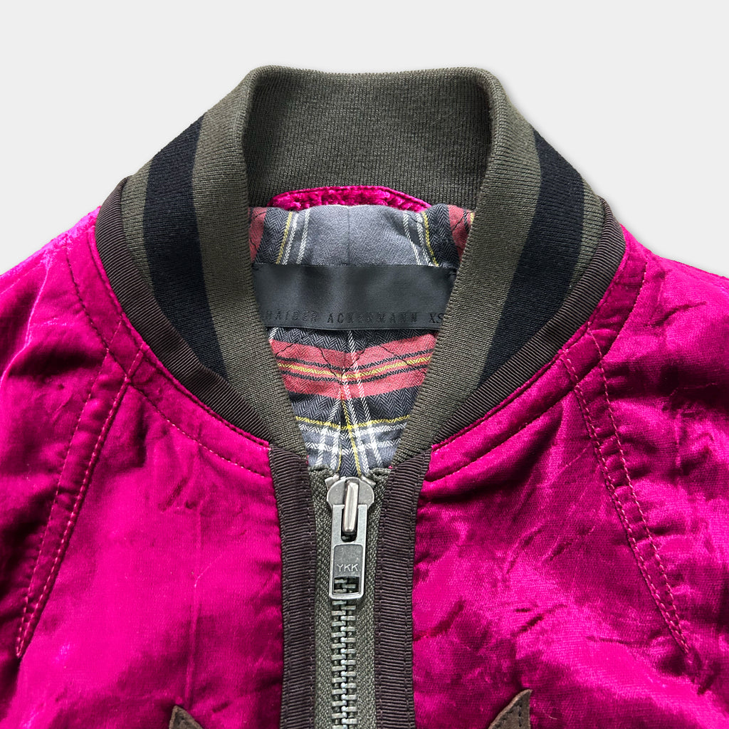A close-up view of a pink velvet jacket with a black collar and zipper.