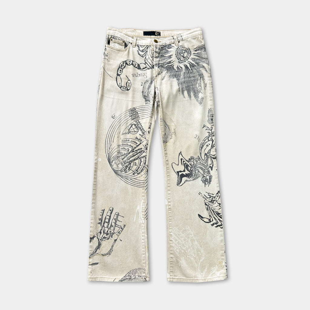 A pair of beige jeans with a unique, intricate design printed on them. The design features various abstract and organic shapes, including what appear to be hands, flowers, and other organic forms.