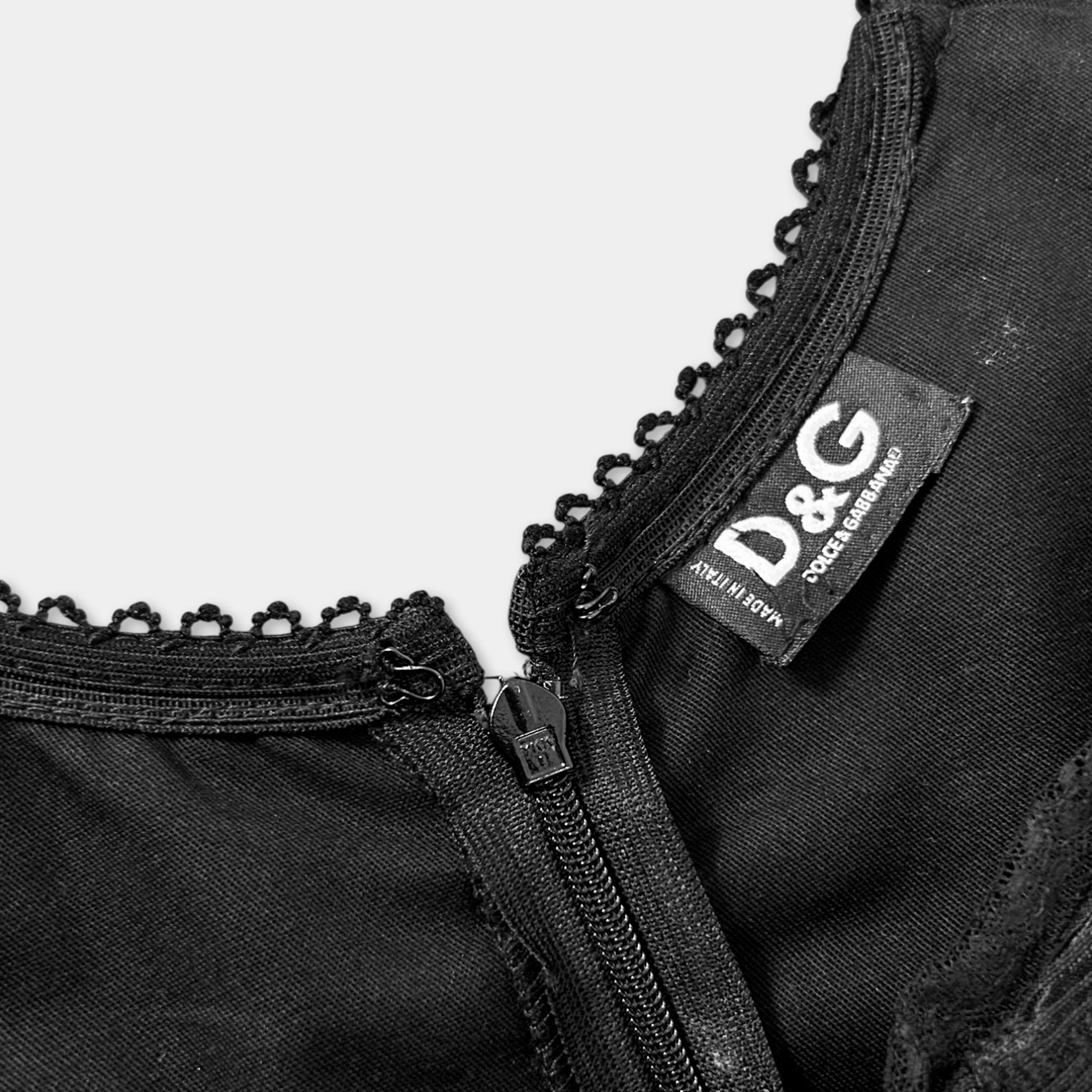 A close-up view of a black zipper on a garment, with a label attached to the collar.