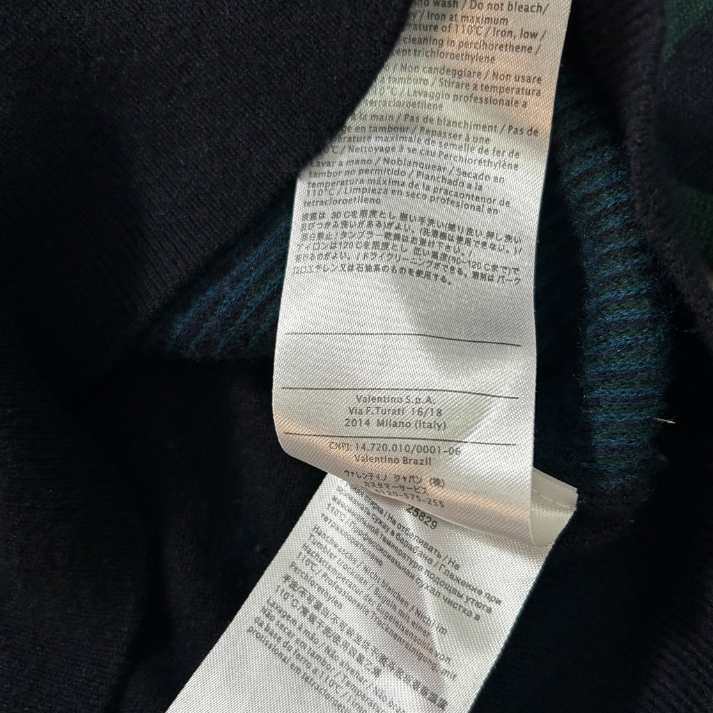 a close-up view of a white label with text on a black background, attached to a dark-colored garment.