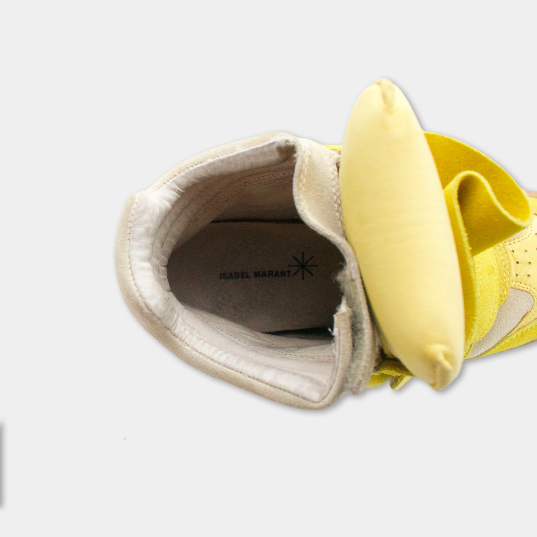A yellow shoe with a yellow banana peel inside, with the text "JEANEL WARANT" visible on the shoe.
