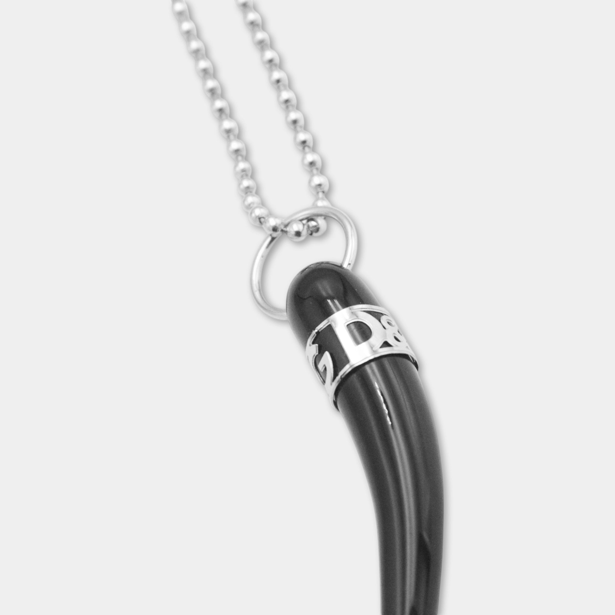 A black pendant with a silver chain and a small metal ring with the letters "D&G" engraved on it.