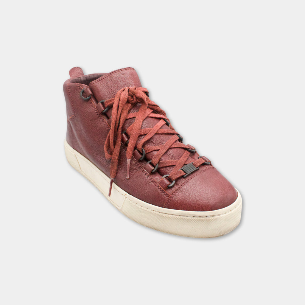 A red and white high-top sneaker with a lace-up design and a white sole.