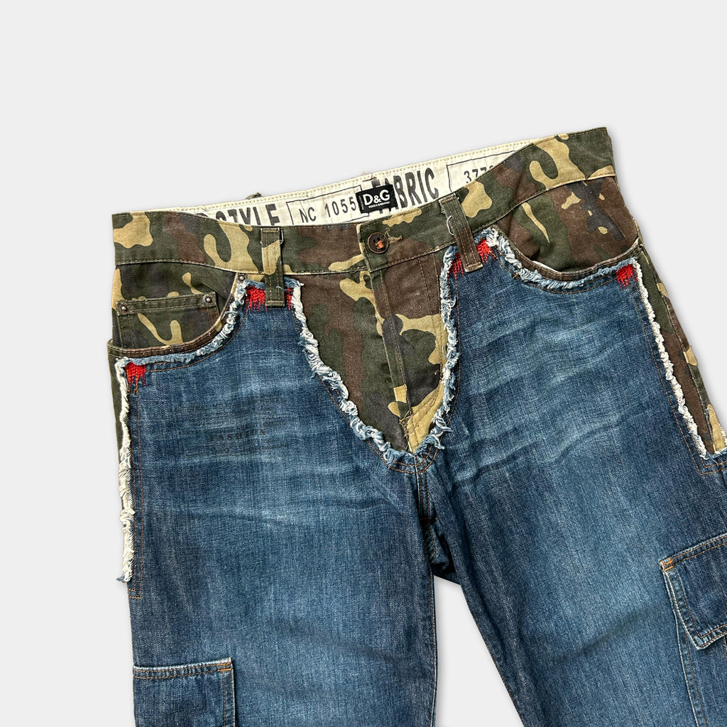 A pair of camouflage-patterned jeans with frayed edges and red stitching on the pockets.