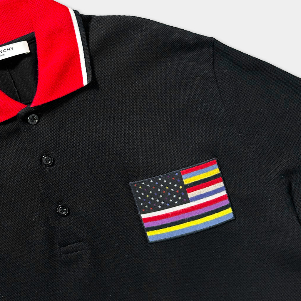a black polo shirt with a red collar and a small American flag patch on the front.