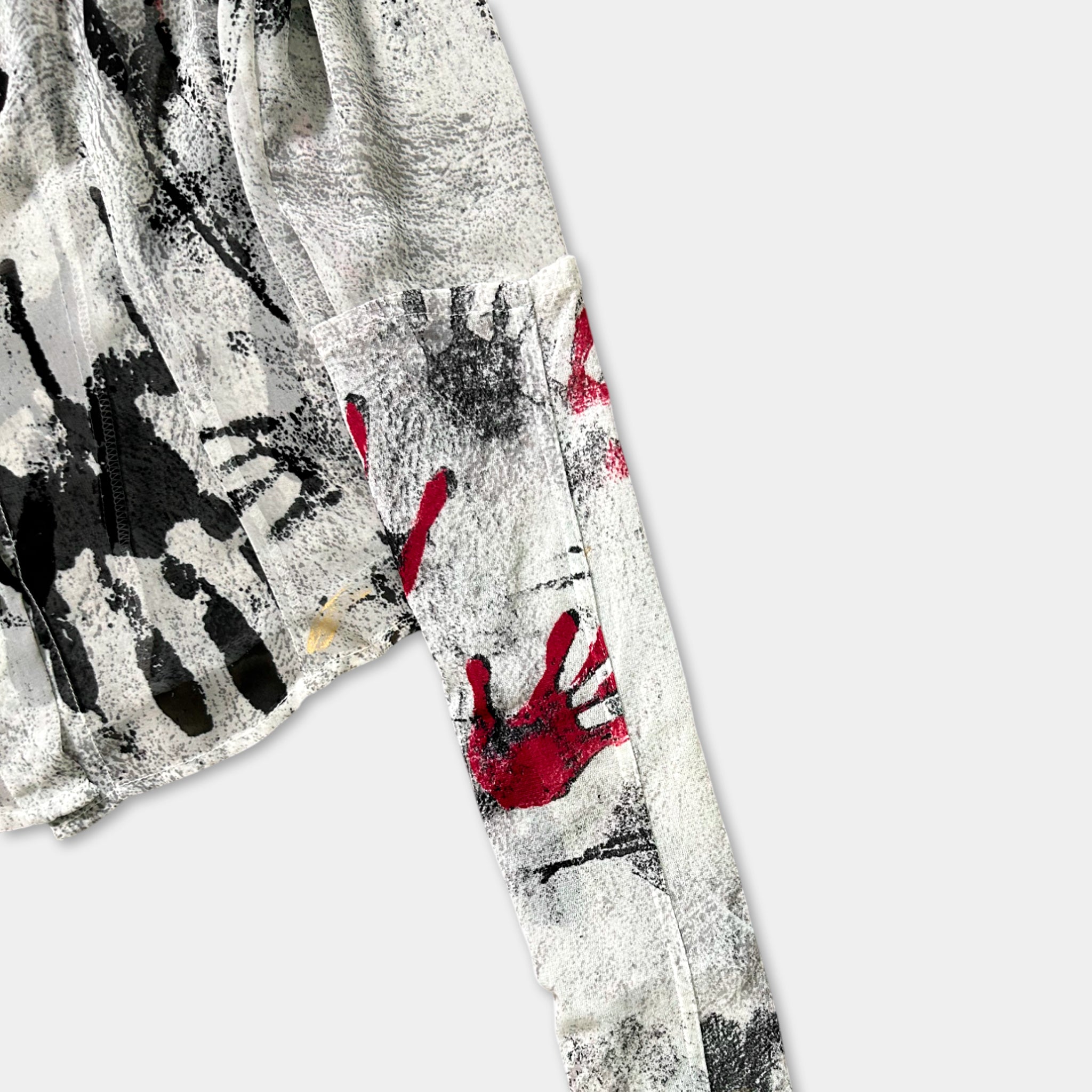 a close-up view of a fabric with a black and white abstract design, including splatters of red and black paint.