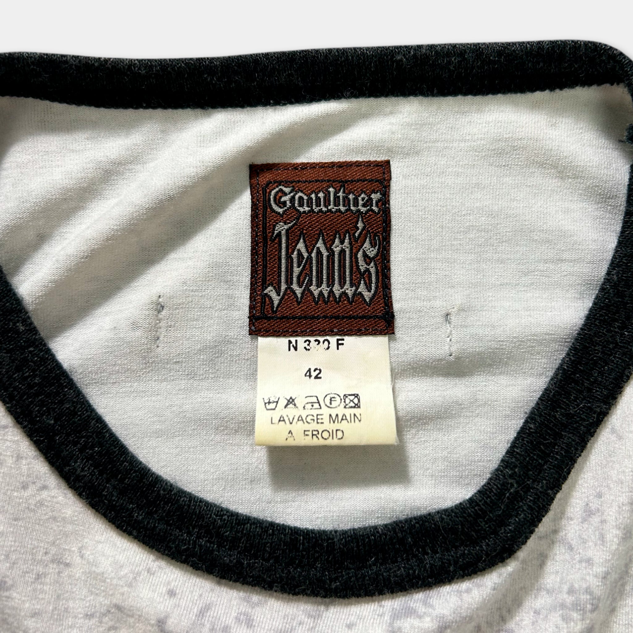 a close-up view of a white t-shirt with a black collar and a label attached to it.