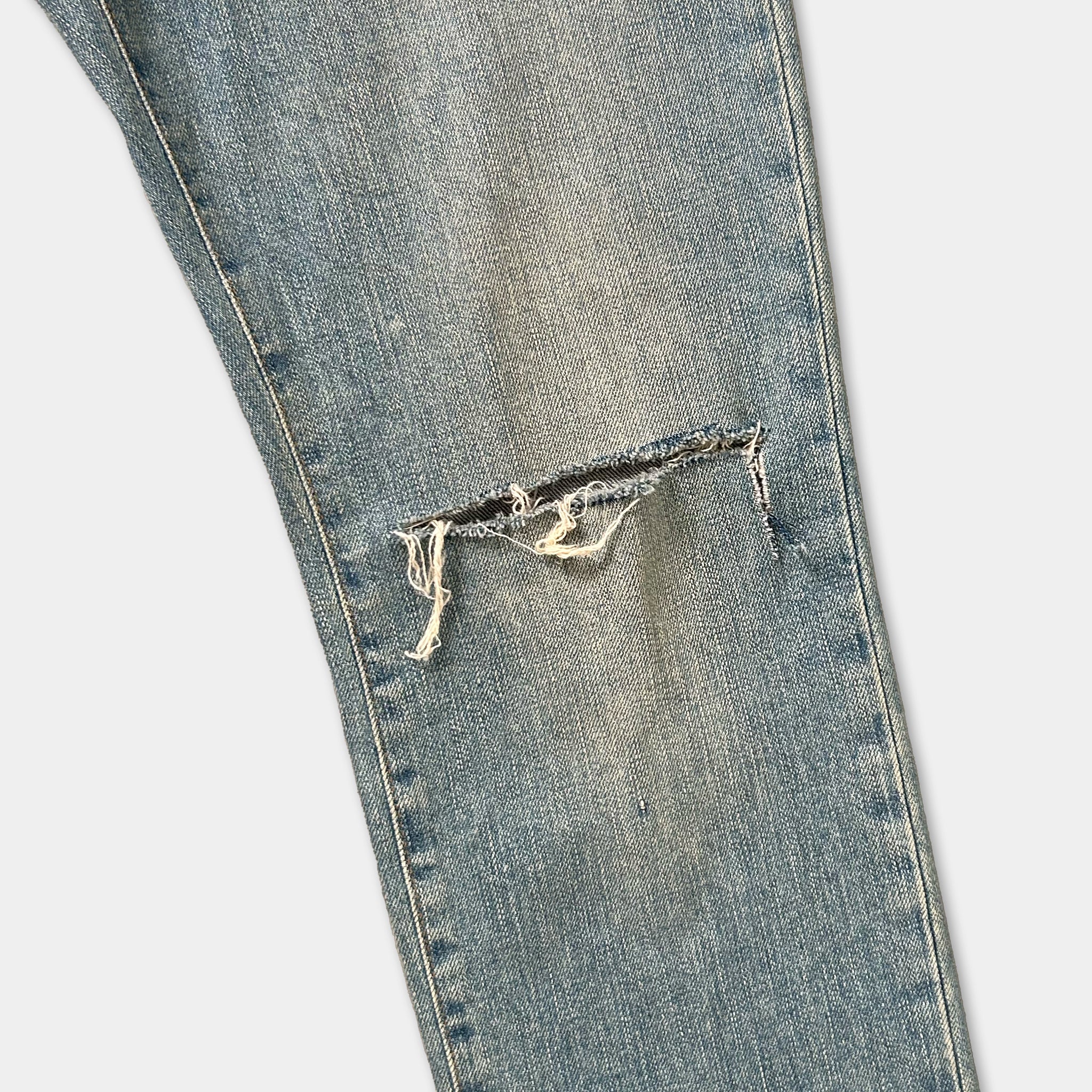 A close-up view of a pair of blue jeans with a noticeable tear in the knee area.