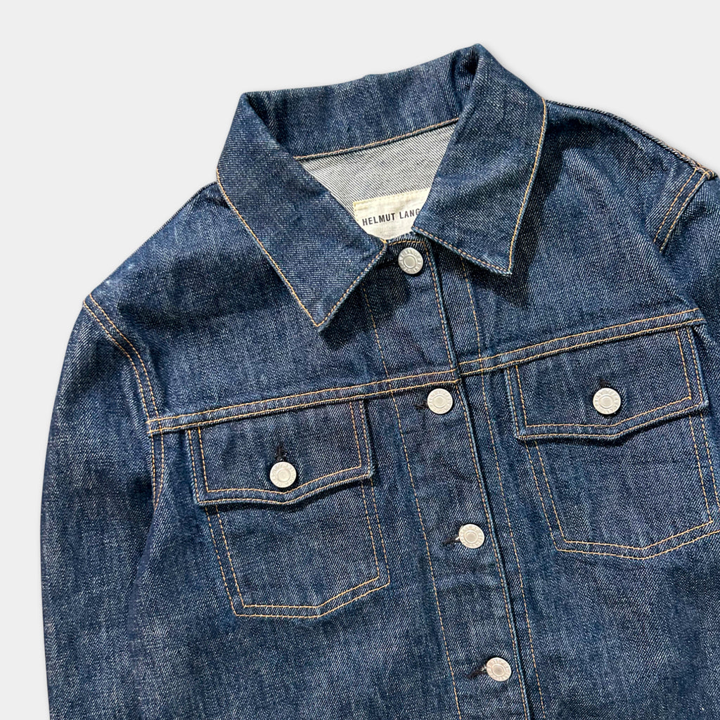 A close-up view of a blue denim jacket with a collar, buttons, and pockets.
