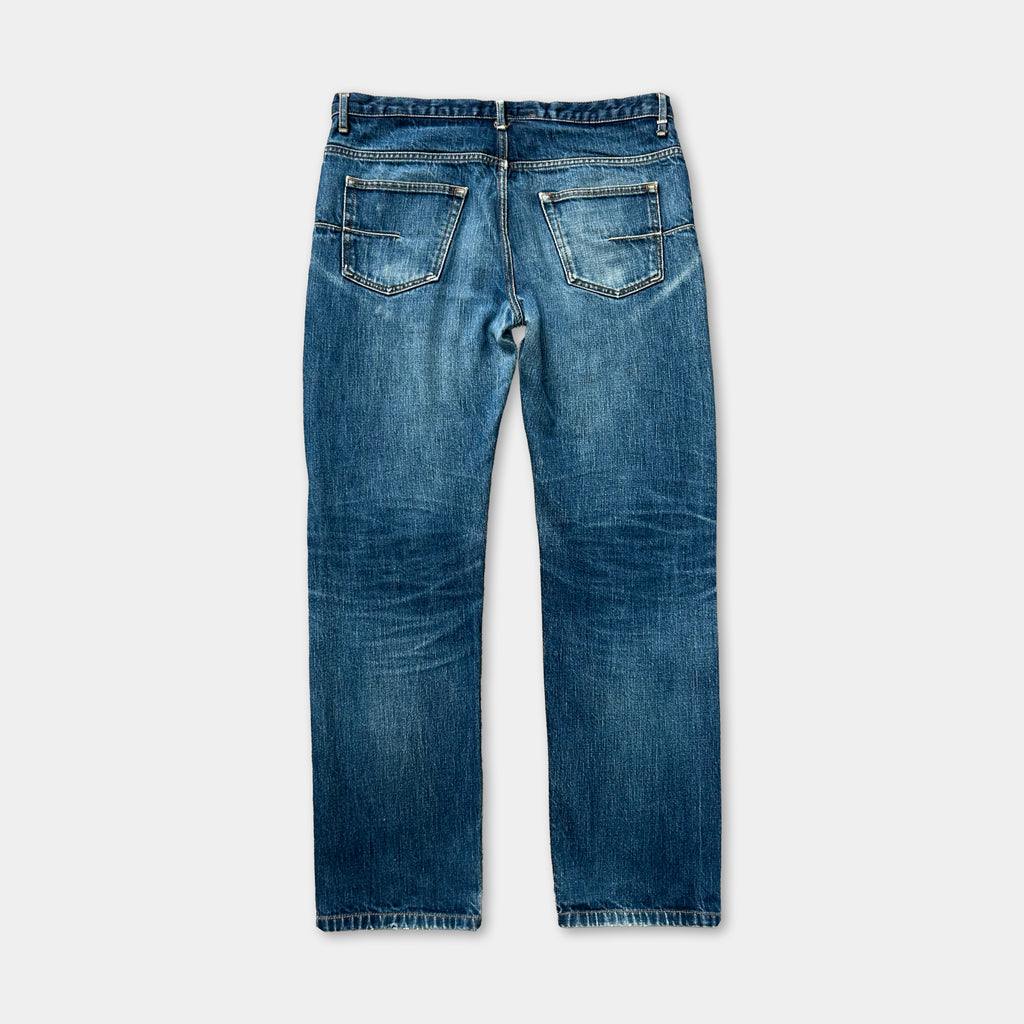 A pair of blue jeans with a classic design, featuring a pocket on the back and a zipper running down the front.
