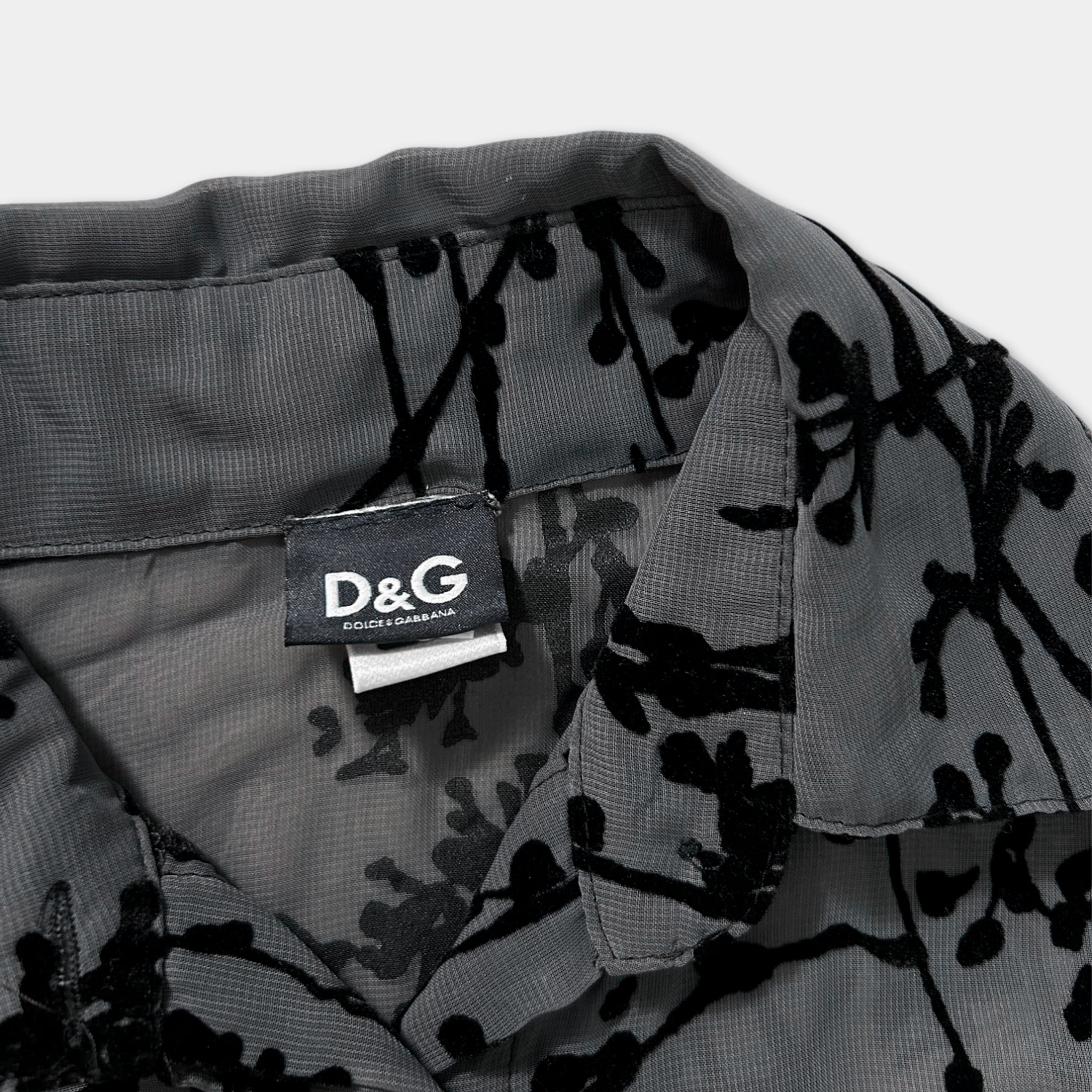 a close-up view of a collar and a tag on a gray fabric with a black floral pattern.