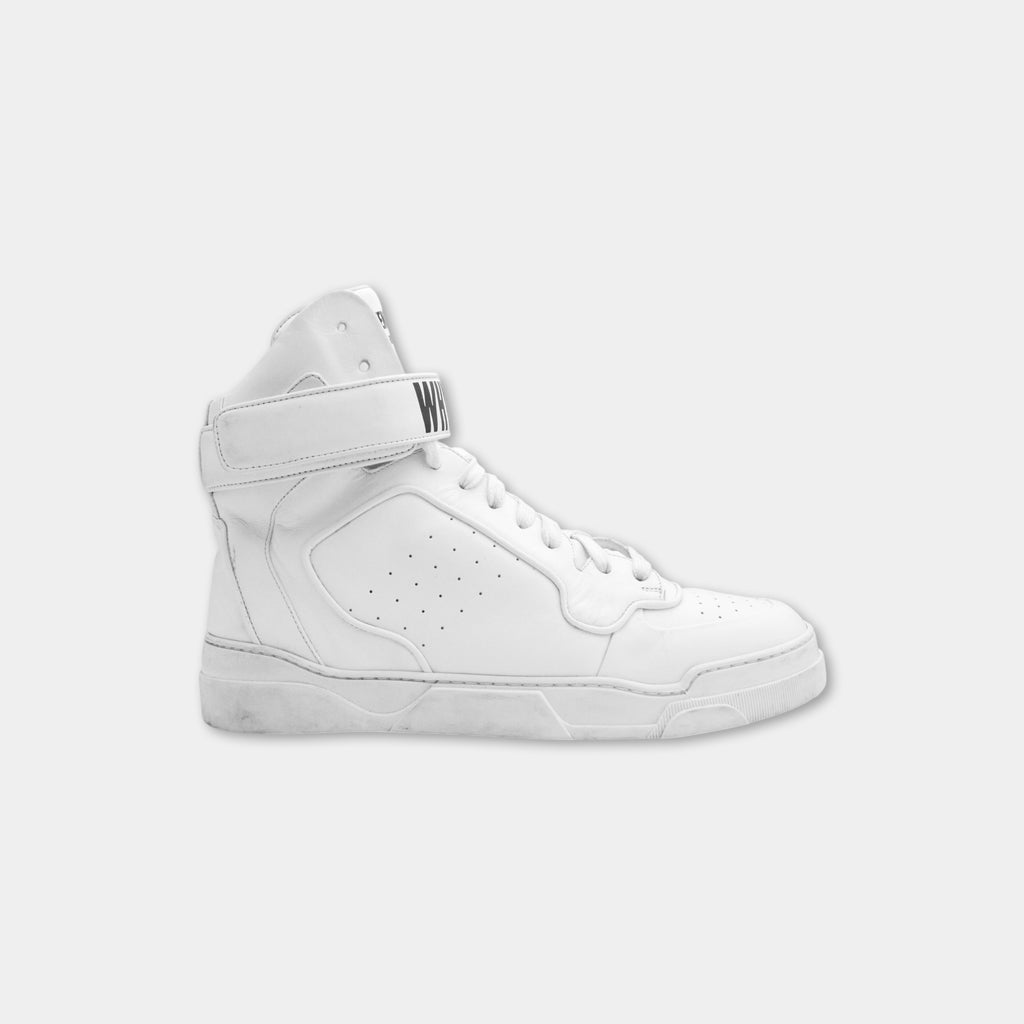 A white high-top sneaker with a strap and laces.